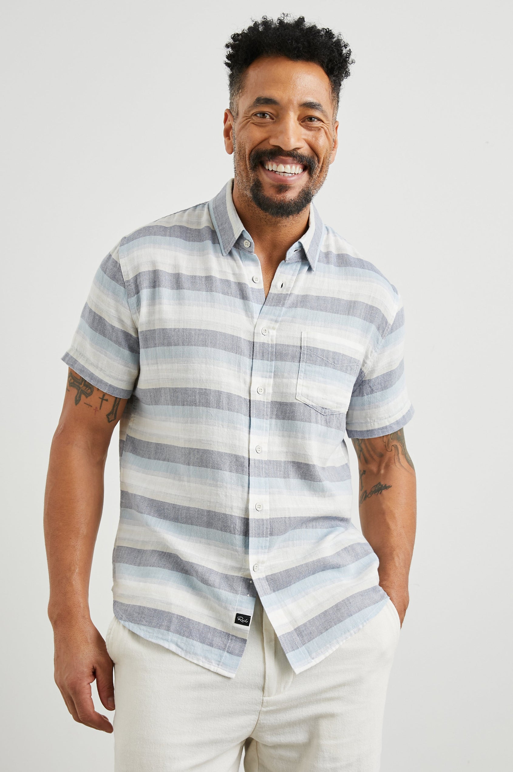 Fairfax Short-Sleeve Button Up with a Chest Patch Pocket in Tabernas Shadow Colorway, with light grey, dark grey, blue and white horizontal stripes - Front View Featured on Model