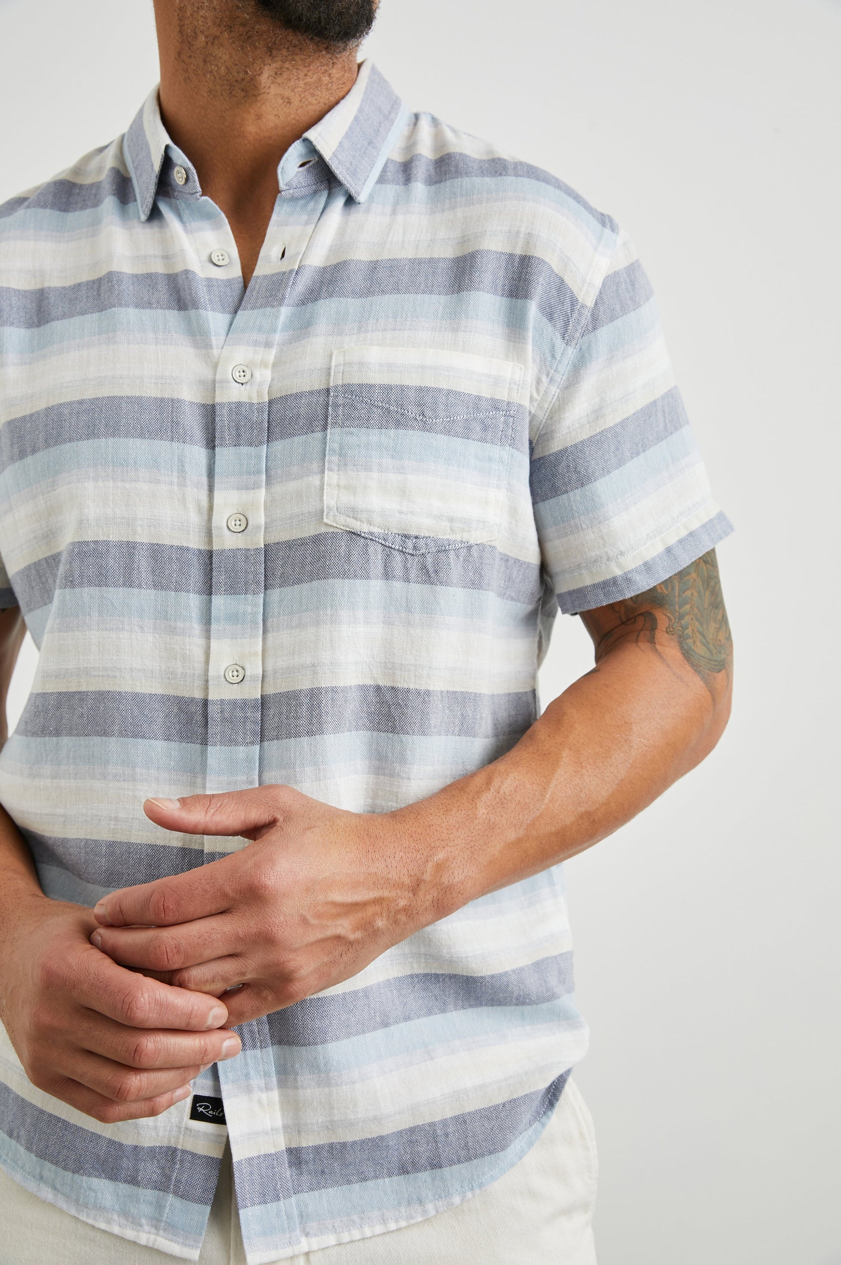 Fairfax Short-Sleeve Button Up with a Chest Patch Pocket in Tabernas Shadow Colorway, with light grey, dark grey, blue and white horizontal stripes - Front View Featured on Model