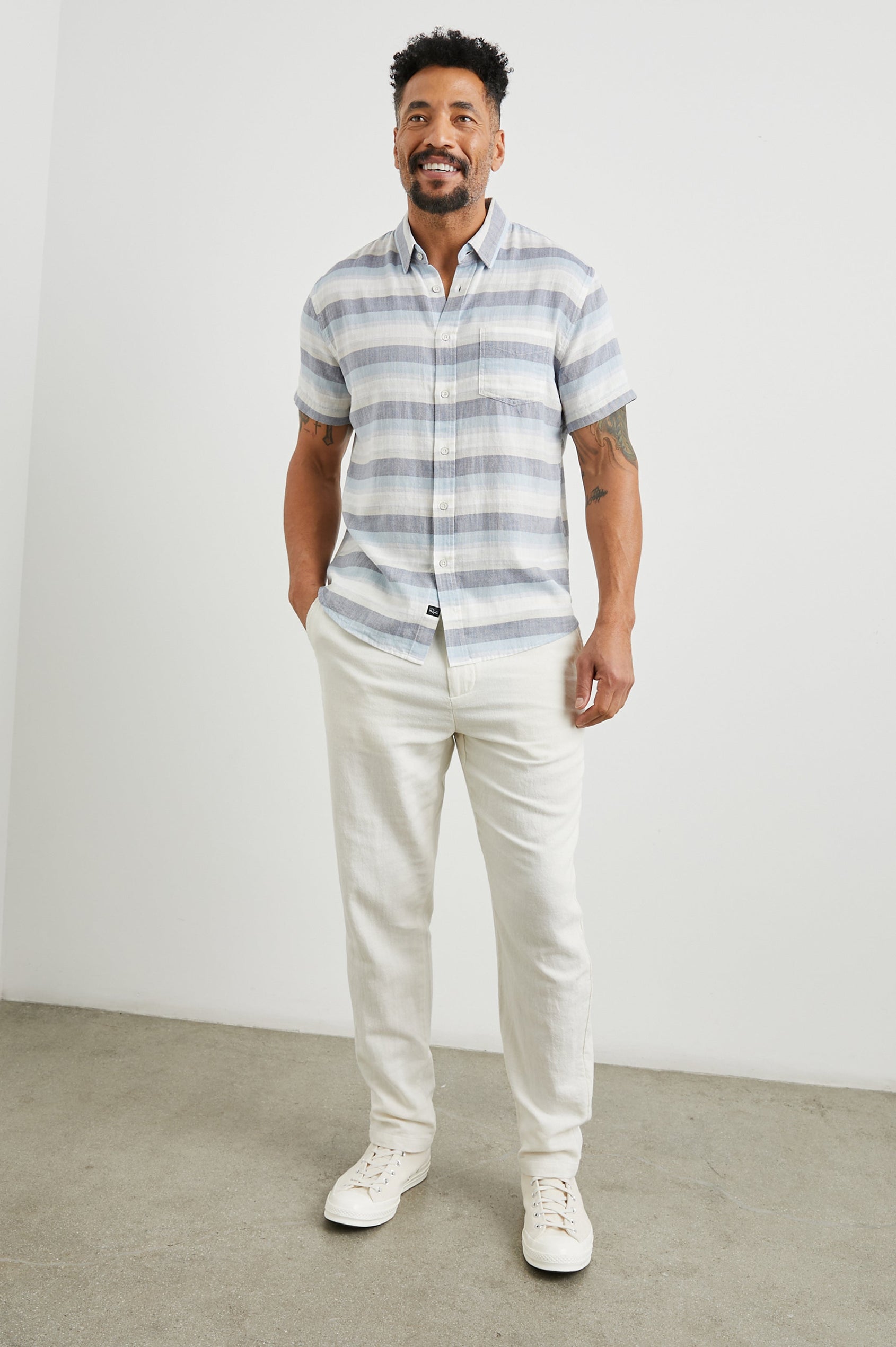 Fairfax Short-Sleeve Button Up with a Chest Patch Pocket in Tabernas Shadow Colorway, with light grey, dark grey, blue and white horizontal stripes - Front Full Body View Featured on Model