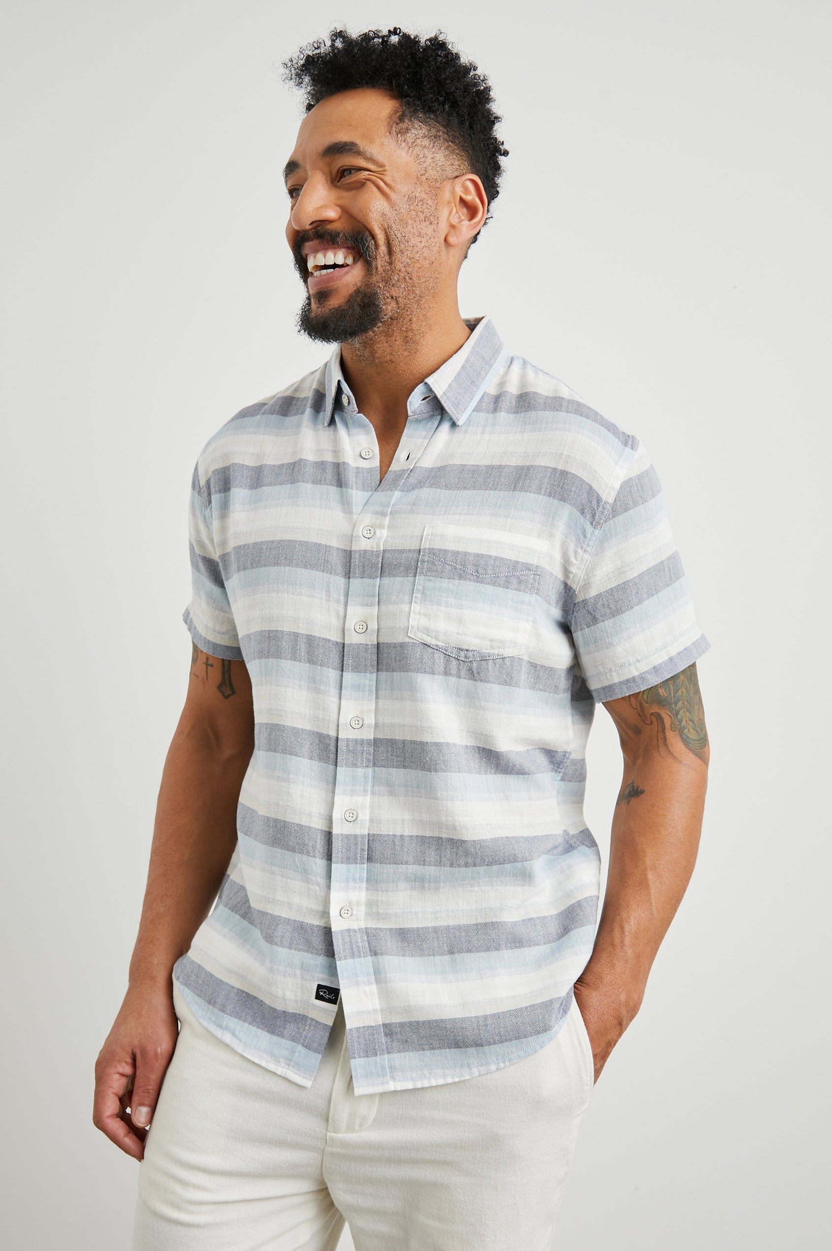 Fairfax Short-Sleeve Button Up with a Chest Patch Pocket in Tabernas Shadow Colorway, with light grey, dark grey, blue and white horizontal stripes - Front View Featured on Model