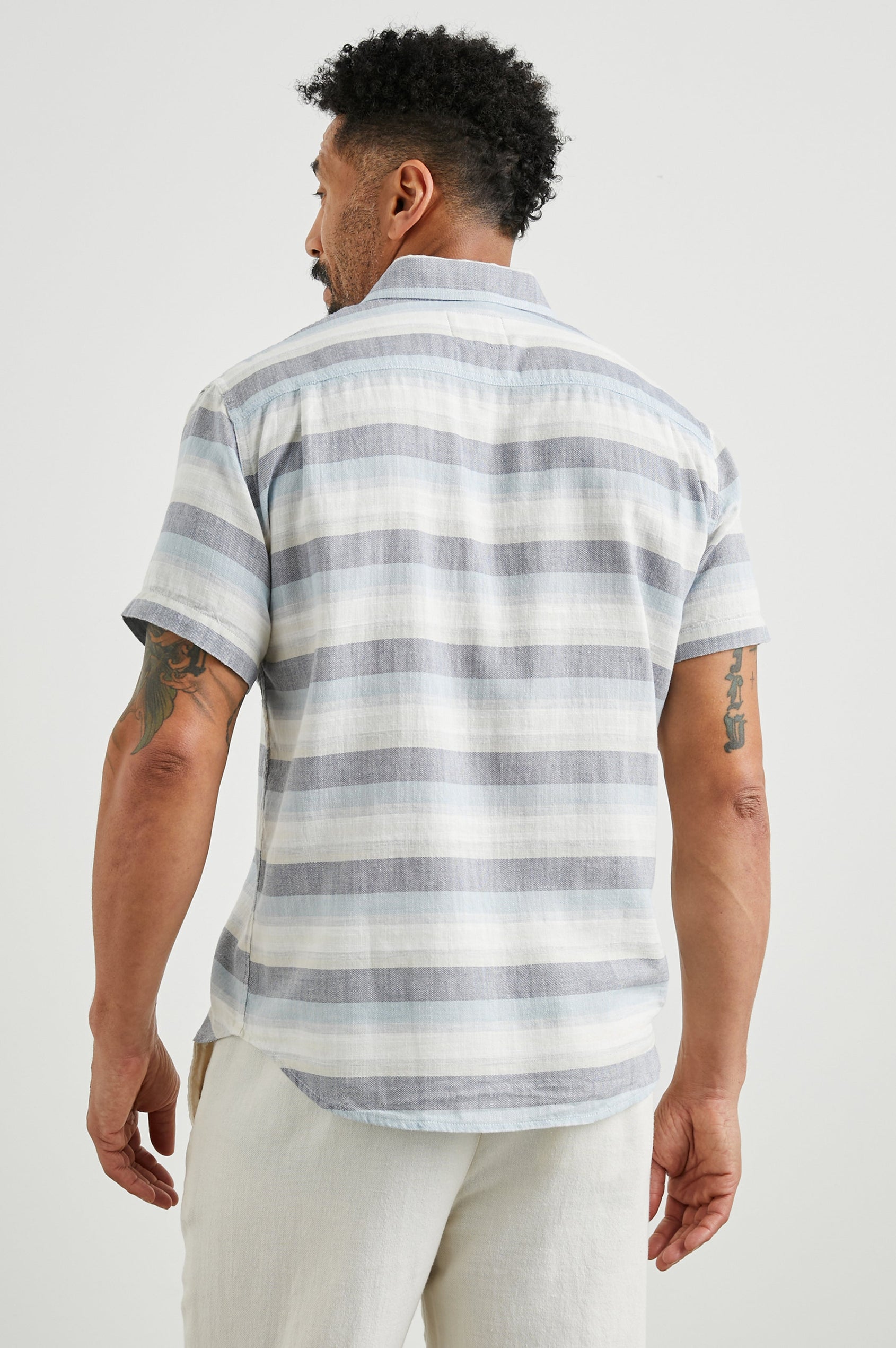 Fairfax Short-Sleeve Button Up with a Chest Patch Pocket in Tabernas Shadow Colorway, with light grey, dark grey, blue and white horizontal stripes - Back View Featured on Model