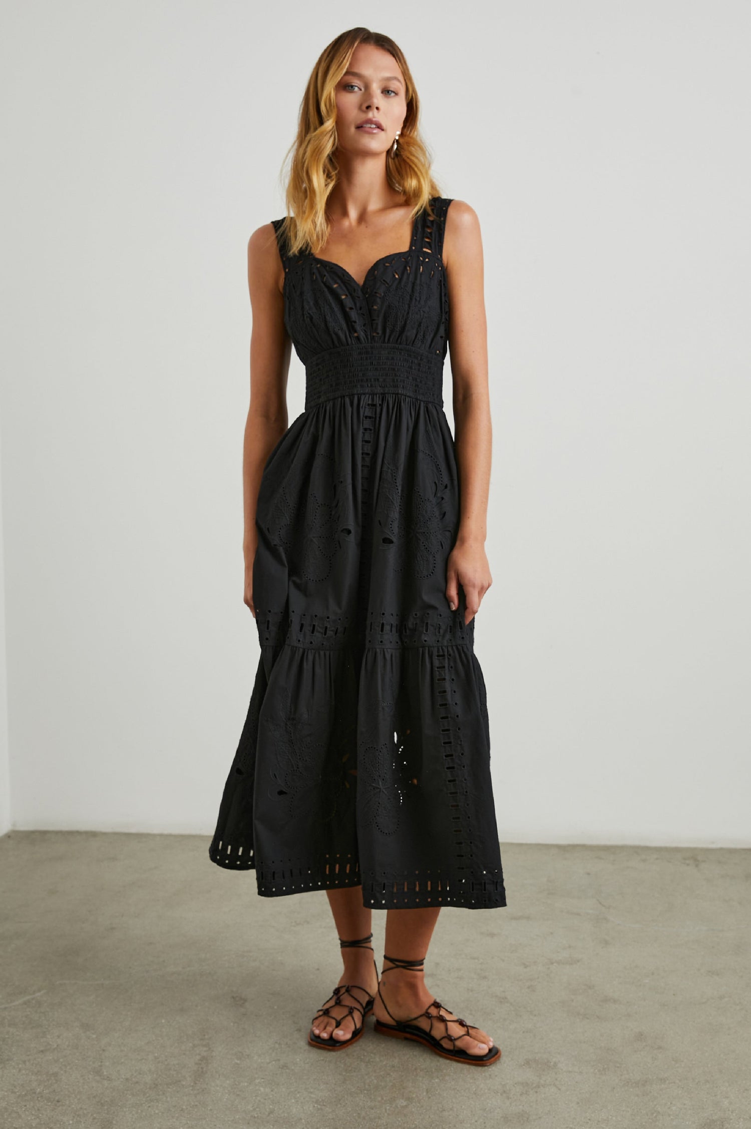 Fawn Sleeveless Midi Dress with Wide Straps, a Sweetheart Neckline, a Cinched Waist and Floral and Geometric Eyelet Details in Black Colorway - Front Full Body View Featured on Model