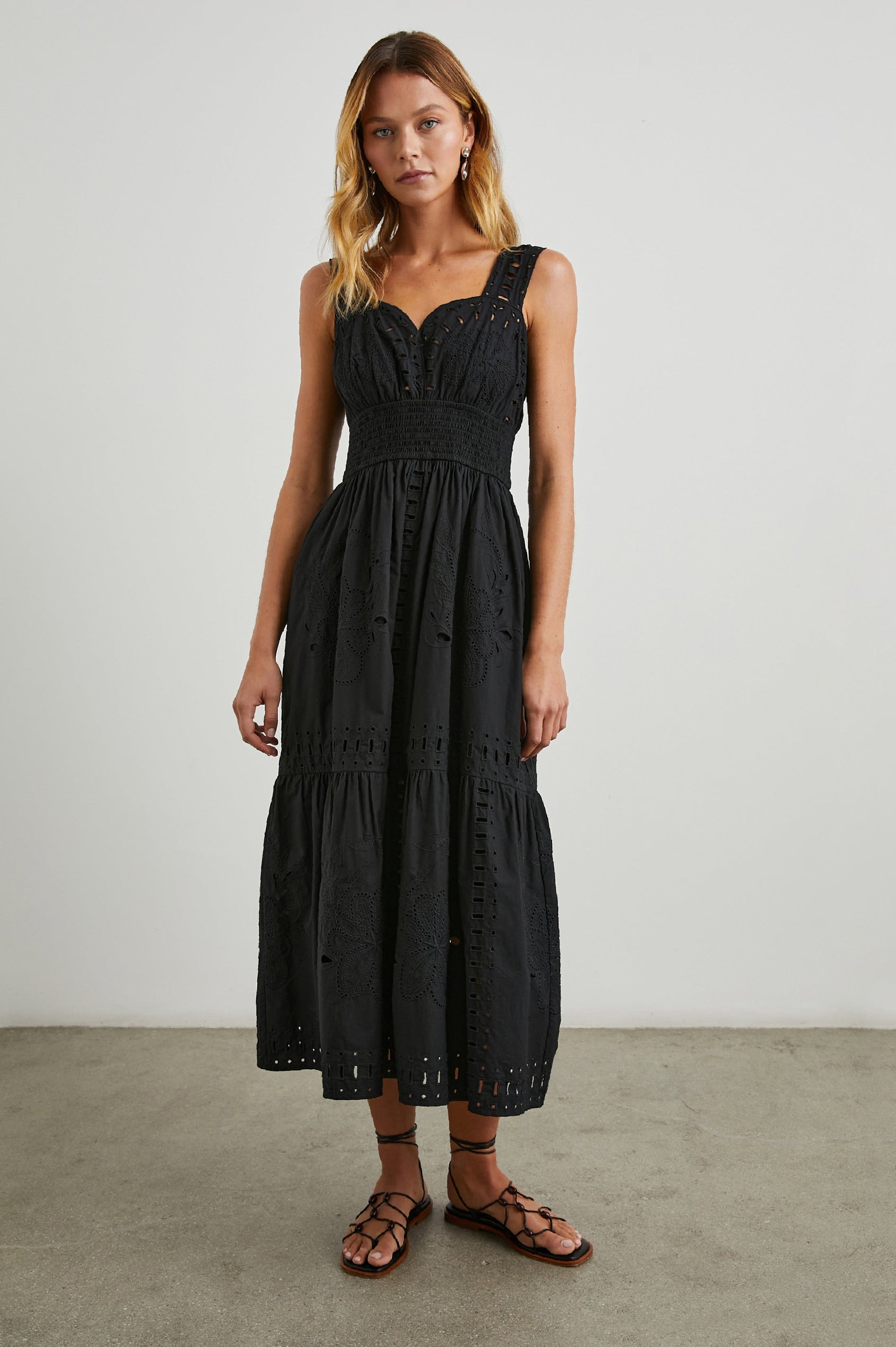 Fawn Sleeveless Midi Dress with Wide Straps, a Sweetheart Neckline, a Cinched Waist and Floral and Geometric Eyelet Details in Black Colorway - Front Full Body View Featured on Model