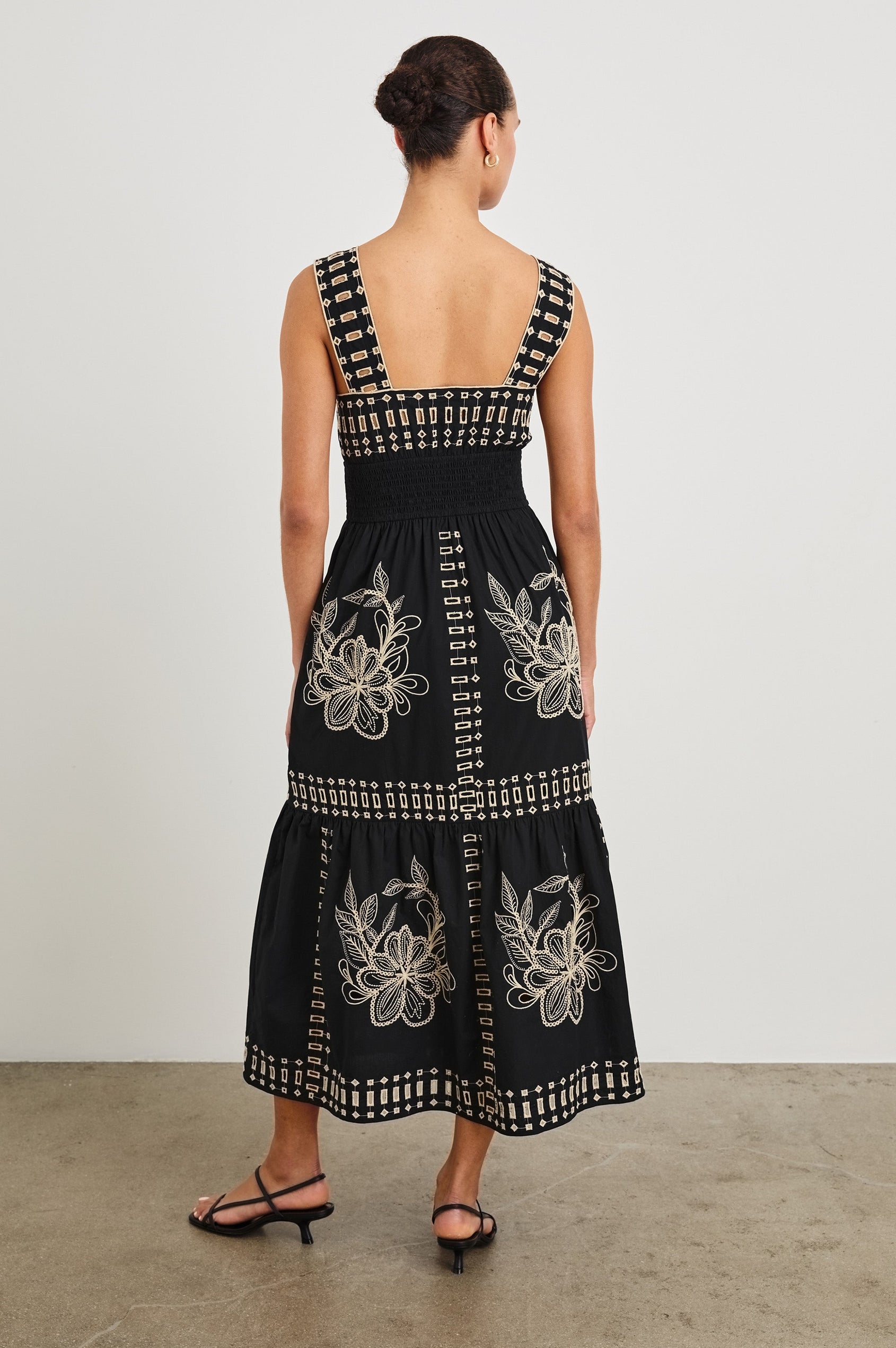 Back view of model wearing our sleeveless, Fawn Midi Dress with Black Tan Embroidery contrast and eyelet details. 