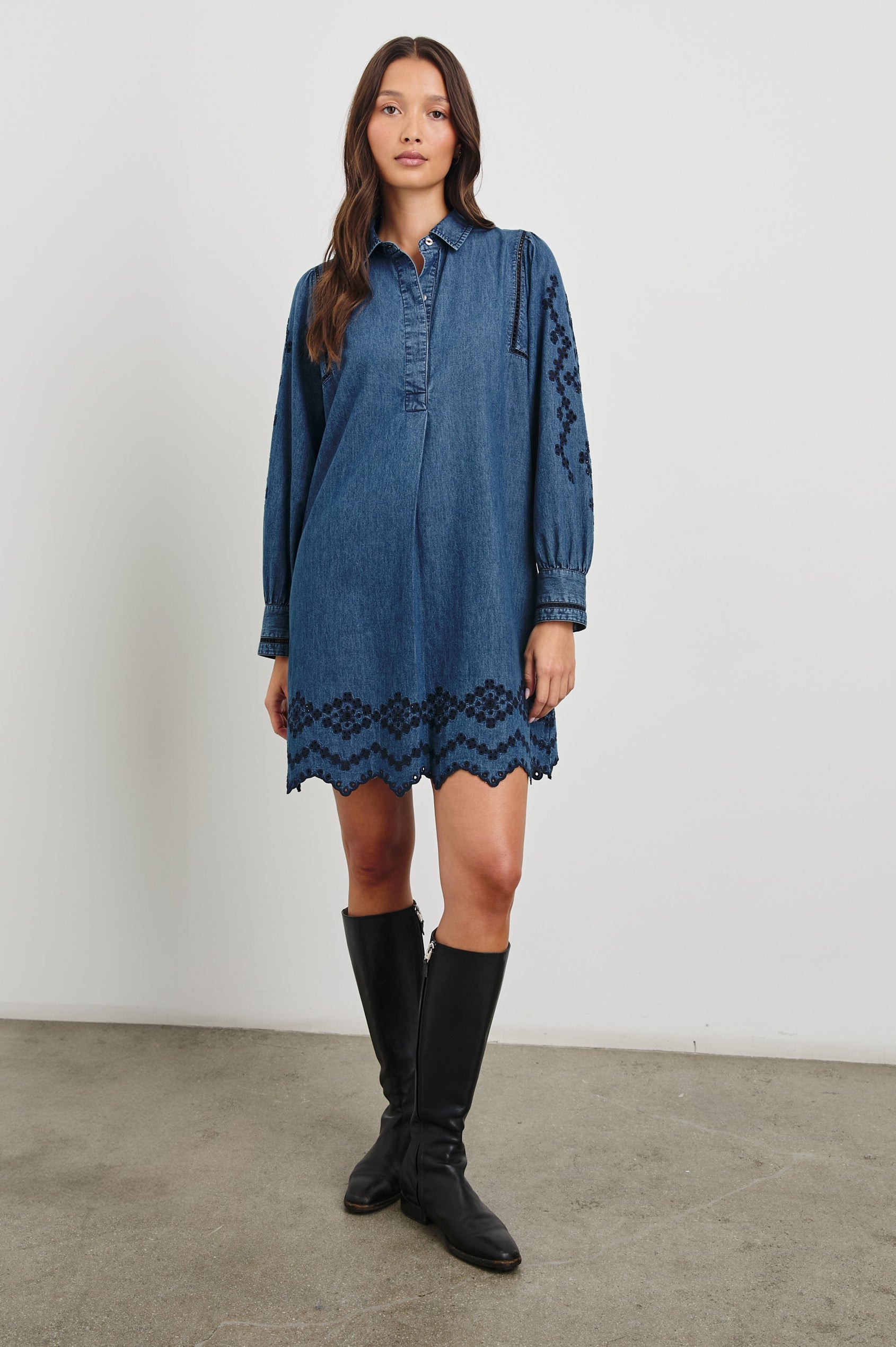 Fernanda Long-Sleeve Mini Dress with Button Cuffs, a Collar, a Placket with Buttons, a Scalloped Hem, a Floral Eyelet Design on the Sleeves and a Floral and Geometric Eyelet Design on the Hem in Dark Vintage Wash Colorway - Front Full Body View Featured on Model