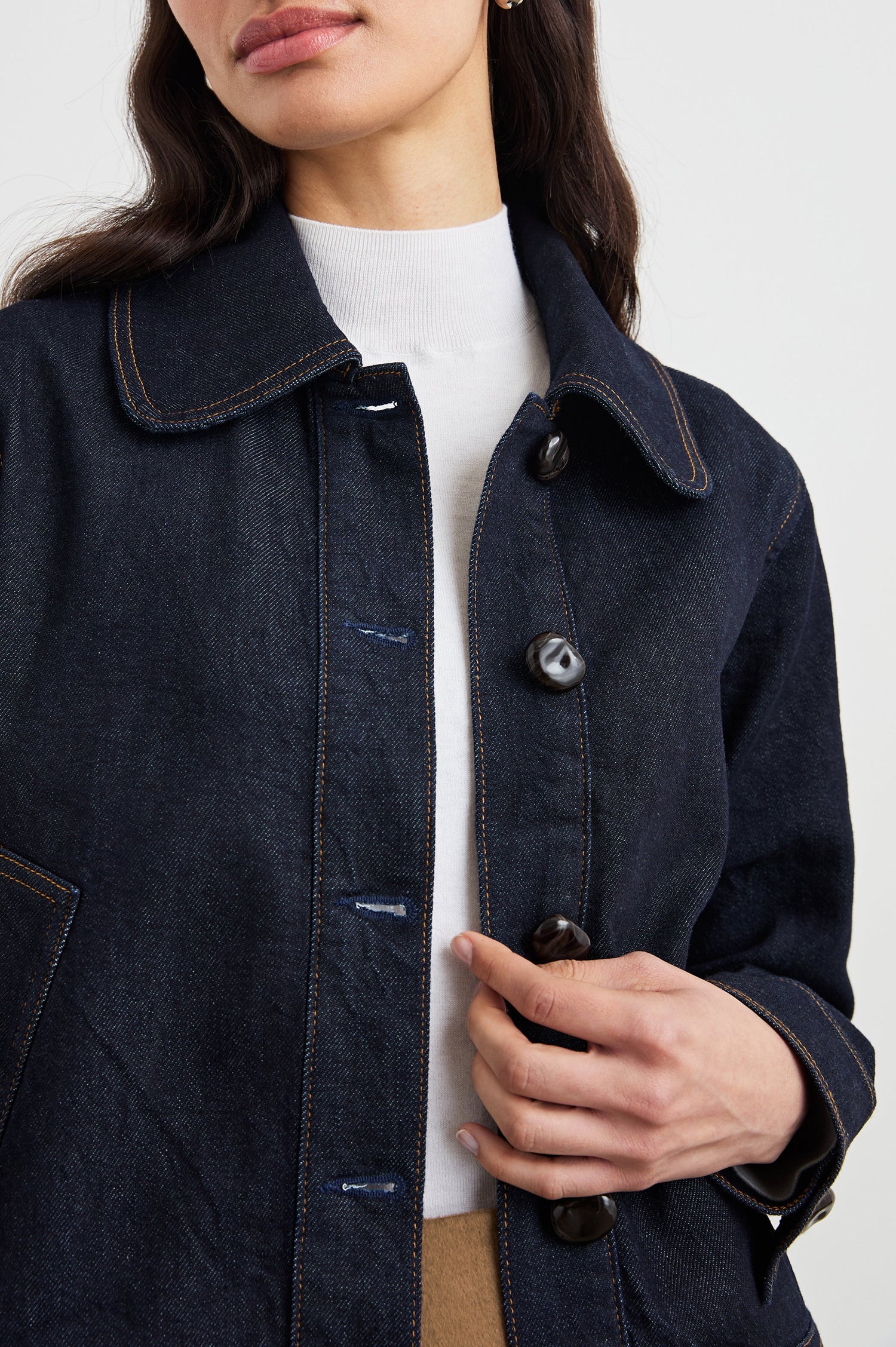 Figueroa Denim Jacket with Button Closure, Two Front Pockets, Adjustable Hem Buckle Tabs and Gold Toned Seam Stitching in Midnight Blues Colorway - Front View Featured on Model