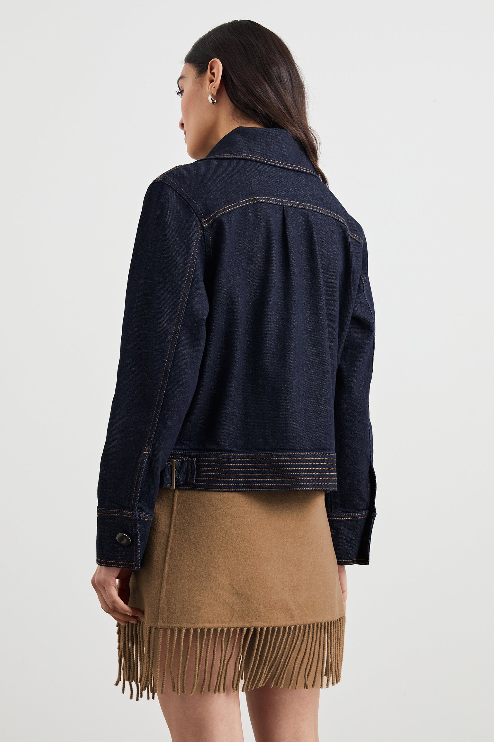 Figueroa Denim Jacket with Button Closure, Two Front Pockets, Adjustable Hem Buckle Tabs and Gold Toned Seam Stitching in Midnight Blues Colorway - Back View Featured on Model
