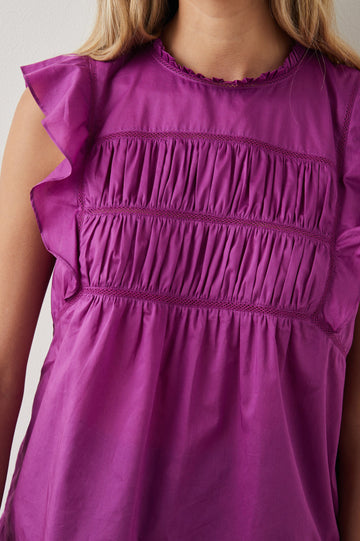 Filomena Short Sleeve Top with Flutter Sleeves, a Ruffled Neck, a Shirred Center Bodice, Lace Inserts and a Buttoned Keyhole at the Back in Berry Colorway - Front View Featured on Model