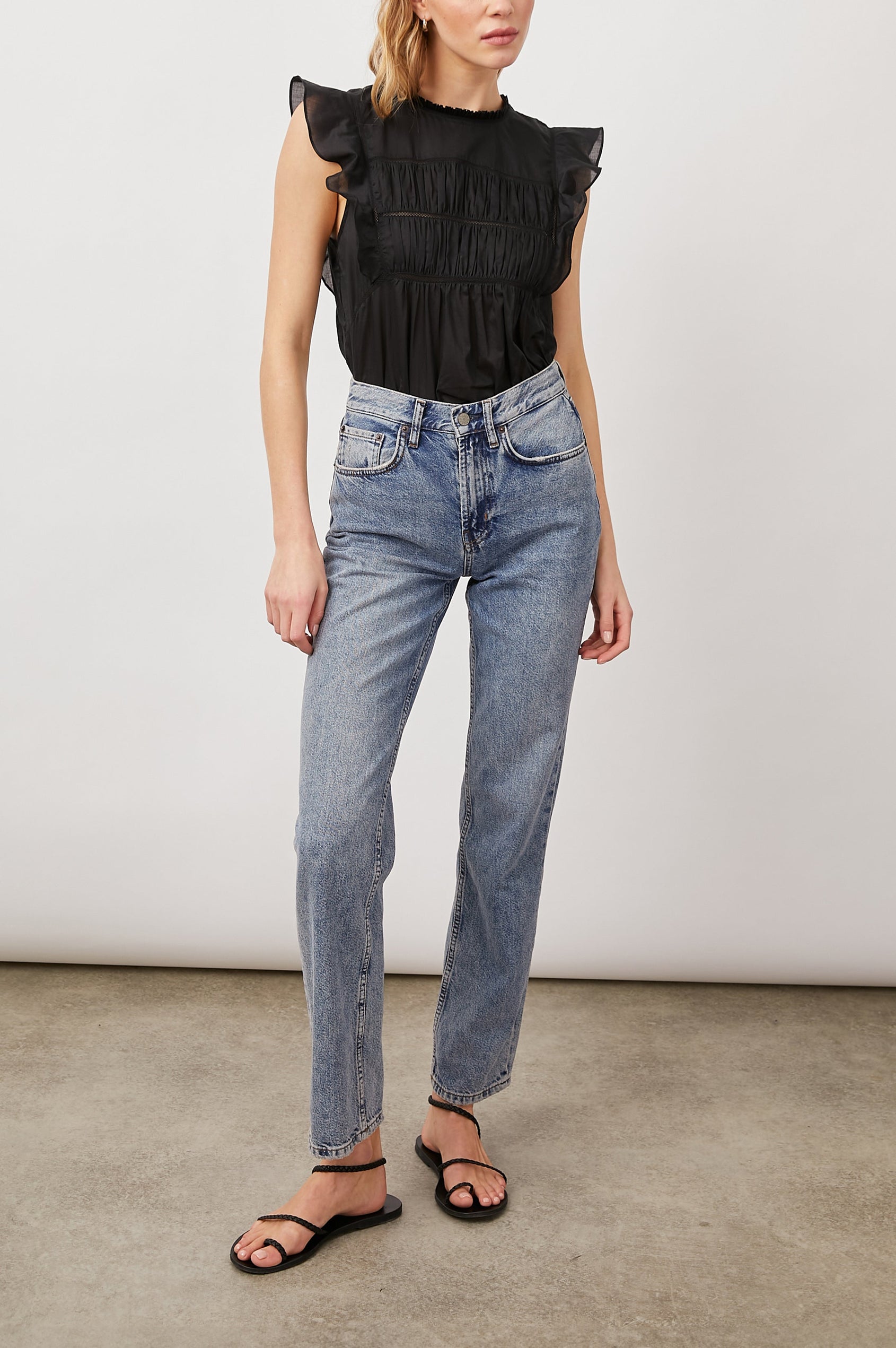 Filomena Short Sleeve Top with Flutter Sleeves, a Ruffled Neck, a Shirred Center Bodice, Lace Inserts and a Buttoned Keyhole at the Back in True Black Colorway - Front Tucked Full Body View Featured on Model