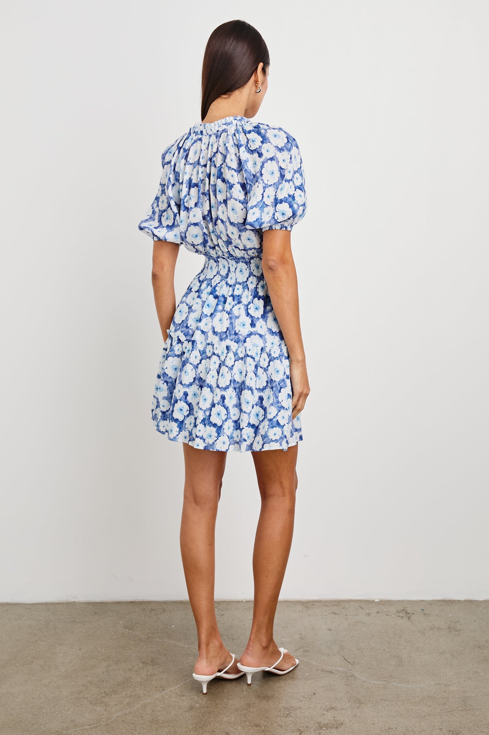 Fiorella Short-Sleeve, Above-Knee Dress with a Shirred Collar and Waist, V-neckline with Ties, Puff Sleeves and a Tiered Skirt in Blue Floral Colorway, Blues and White - Back Full Body View Featured on Model
