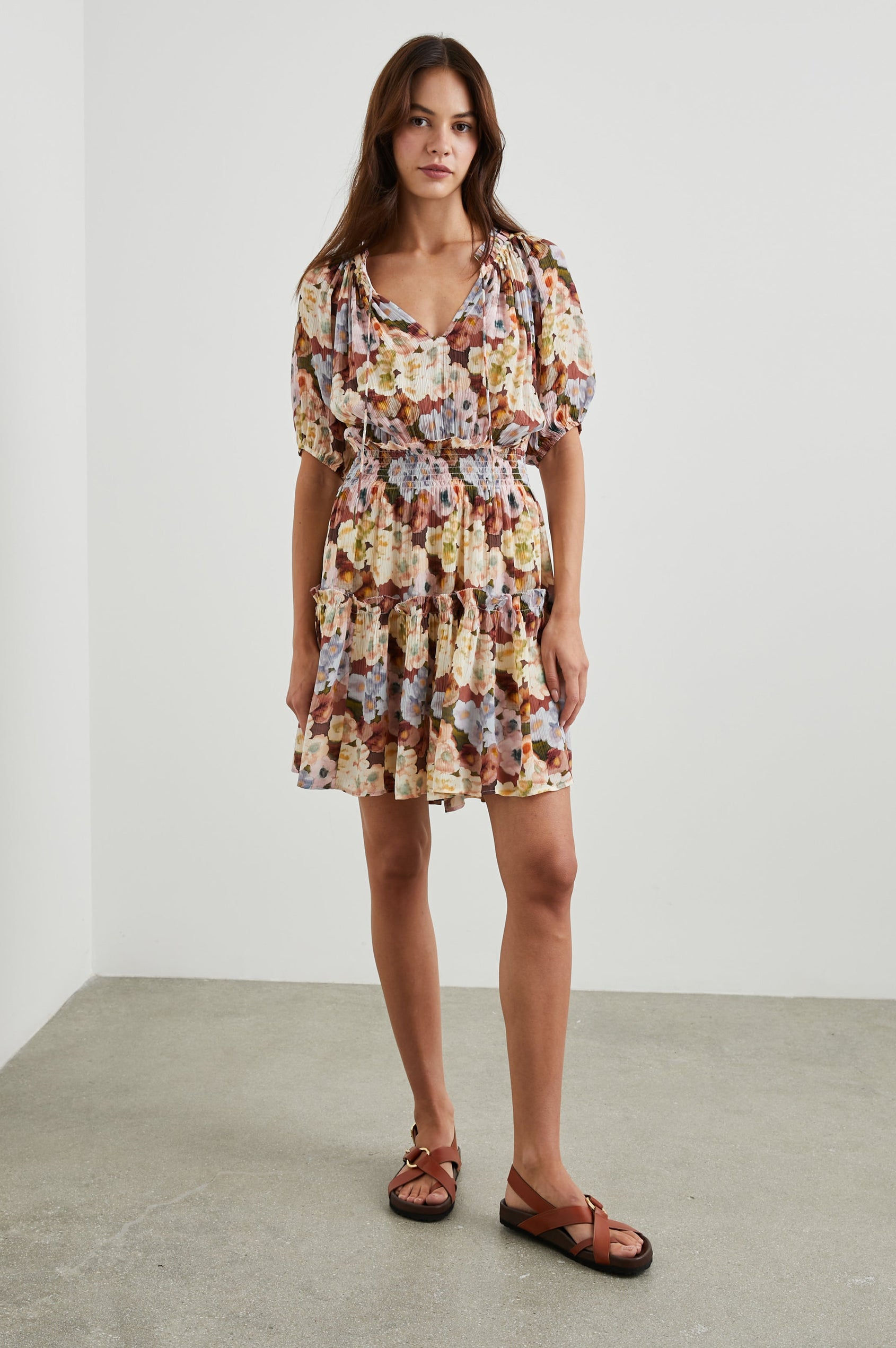 Fiorella Short-Sleeve, Above-Knee Dress with a Shirred Collar and Waist, V-neckline with Ties, Puff Sleeves and a Tiered Skirt in Painted Floral Colorway, with browns, yellows and blues - Front Full Body View Featured on Model