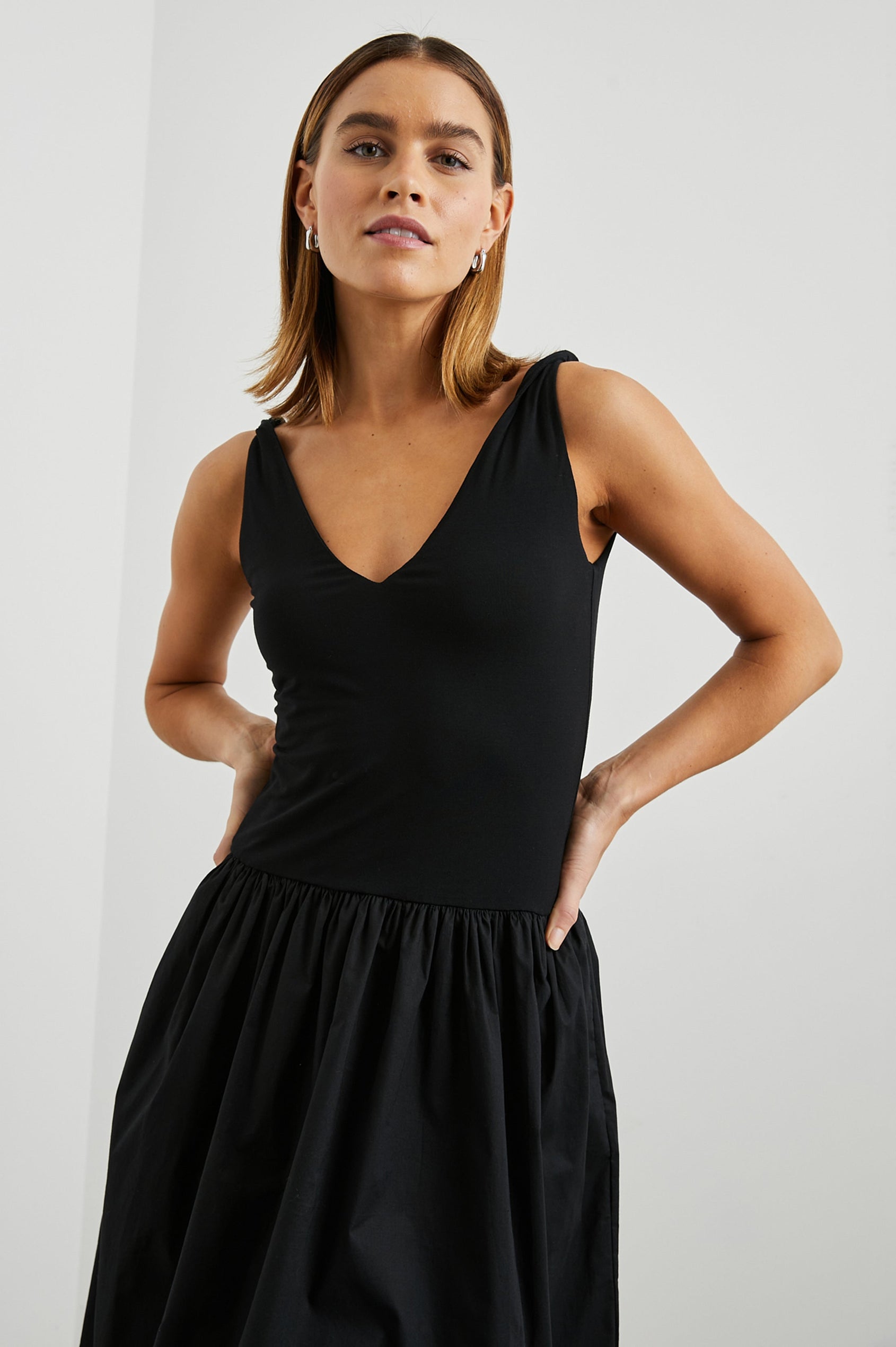 Franca Sleeveless Midi Dress with Twisted Shoulder Straps, a deep V Neck and Pleats at the Waist in Black Colorway - Front View Featured on Model
