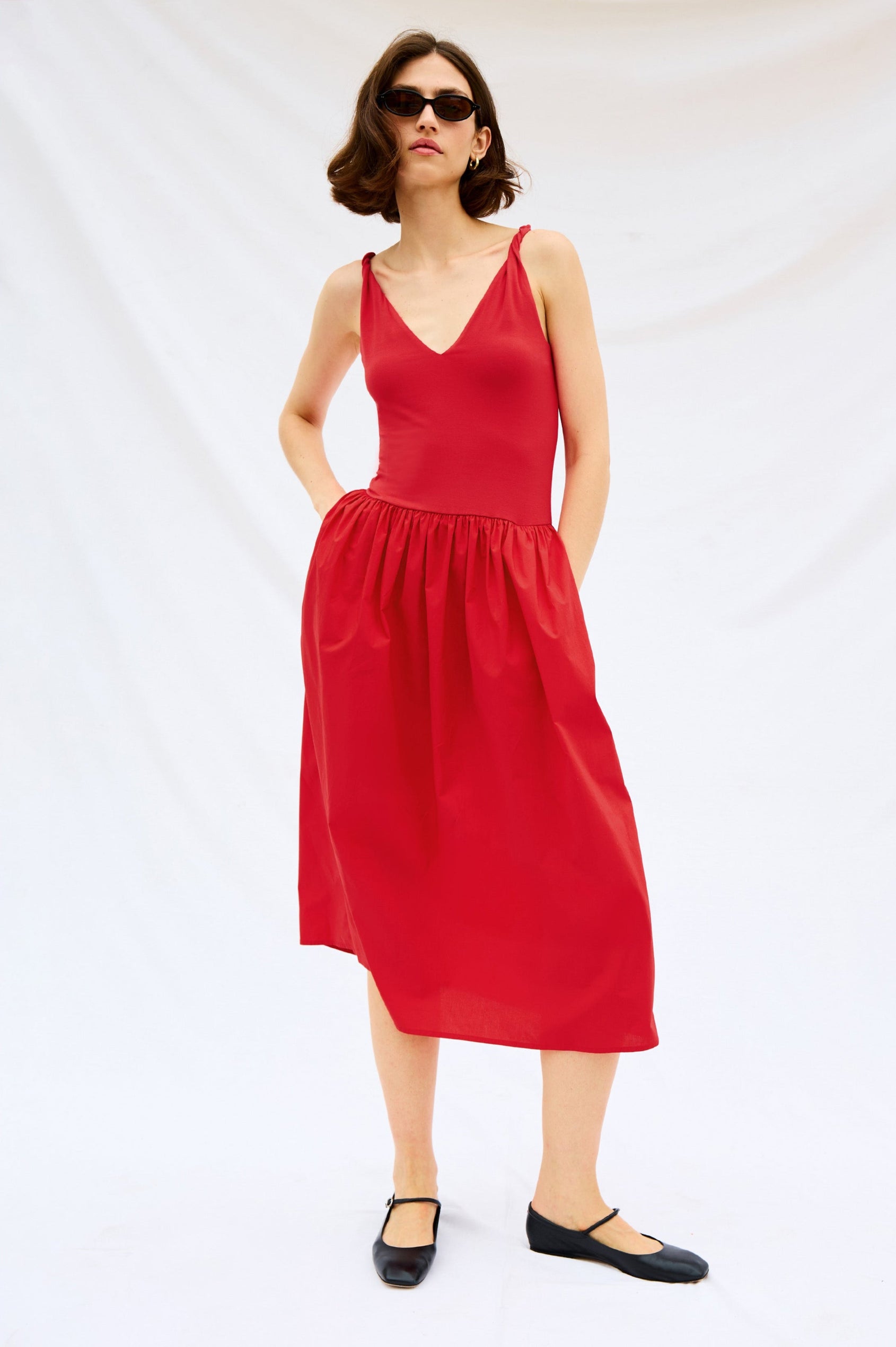Franca Sleeveless Midi Dress with Twisted Shoulder Straps, a deep V Neck and Pleats at the Waist in Cherry Colorway - Front Full Body Stylized View Featured on Model