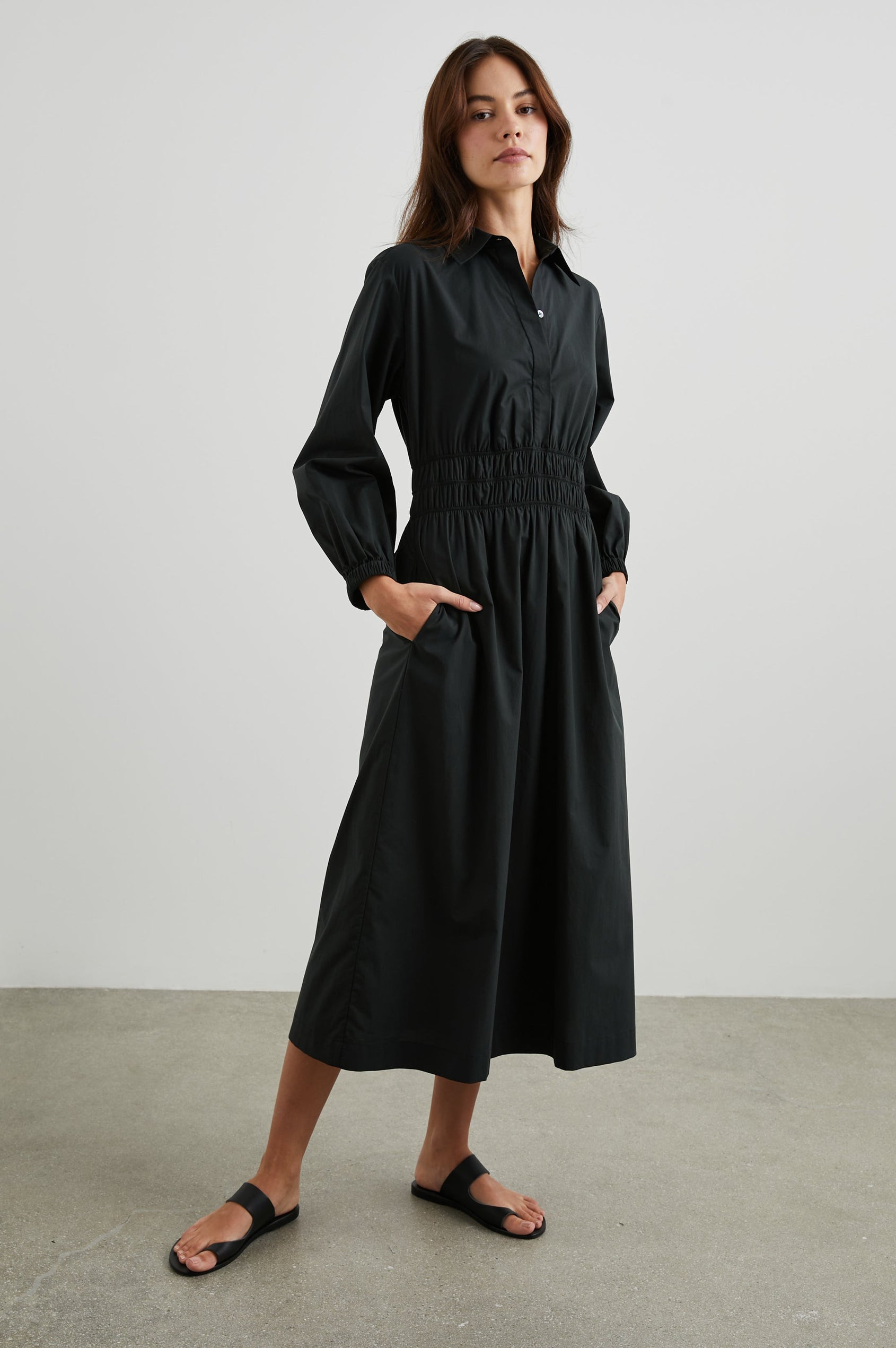 Fraya Long-Sleeve Midi Dress with a Concealed Button Placket on the Bodice, a Collar, a Shirred Waist, and Two Hip Pockets in Black Colorway - Front Full Body View Featured on Model 