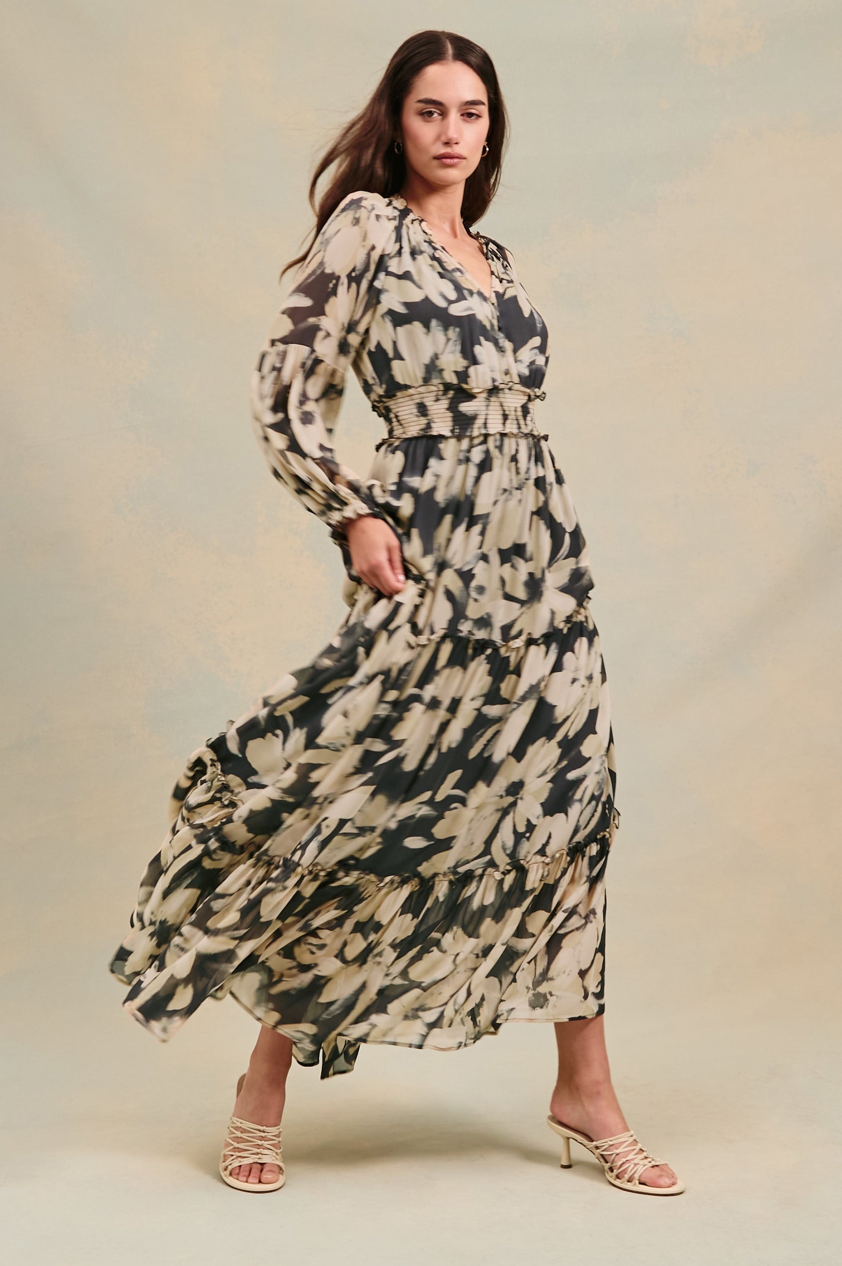 Frederica long sleeve flowy maxi dress with smocked neckline and waist and tiered skirt in Charcoal Lily - stylized full body view on model, in motion