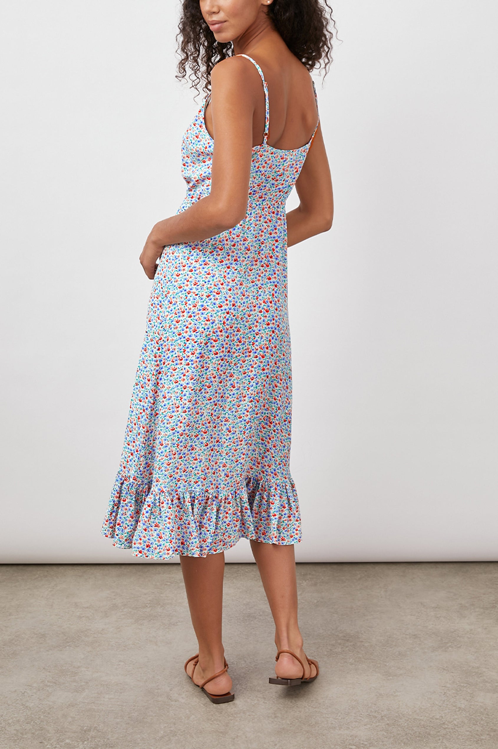 Frida Midi Dress with a Deep V Neck, Adjustable Spaghetti Straps, a Ruffled Hem, Drawstring Waist Ties and Buttons Down the Front in Wild Daisies Colorway, blue, Red and Pink Daisies on White - Back Full Body View Featured on Model