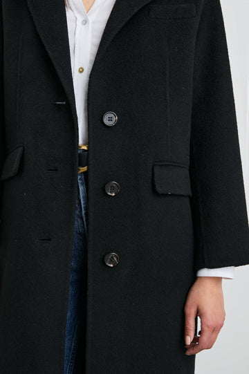 Gallery Below-the-Knee Coat with Three-Button Closure, Notched Lapels, and Two Front Flap Pockets in Black Colorway - Front View Featured on Model