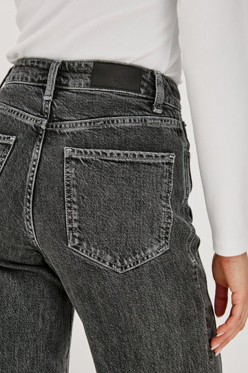 Getty Twist Seam Wide Leg Denim Pants with a Diagonal Seam Across the Leg, Belt Loops, Two Front Pockets and Two Back Patch Pockets in Washed Charcoal Colorway - Back Detail View Featured on Model
