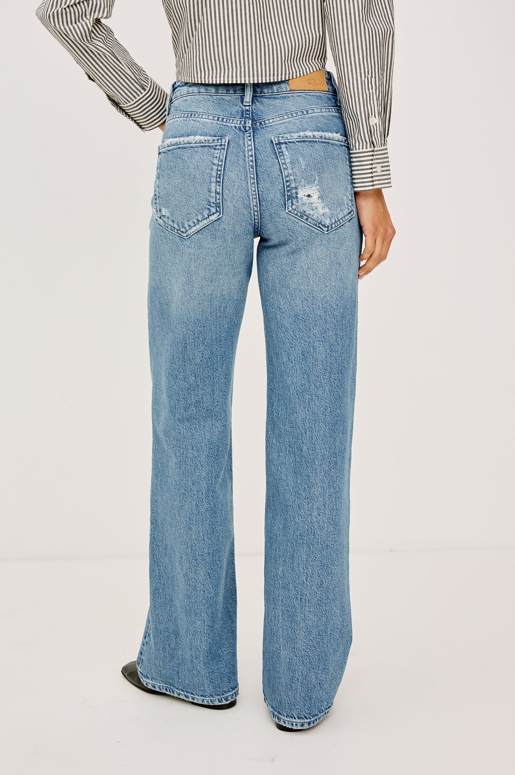 Fremont Low Rise Bootcut Jean in Light Stretch Denim With Extended Inseam, 5-Pockets, Distressed Details, Belt Loops, and Zip-Fly Closure in Wild West Colorway - Lower Body Back View Featured on Model