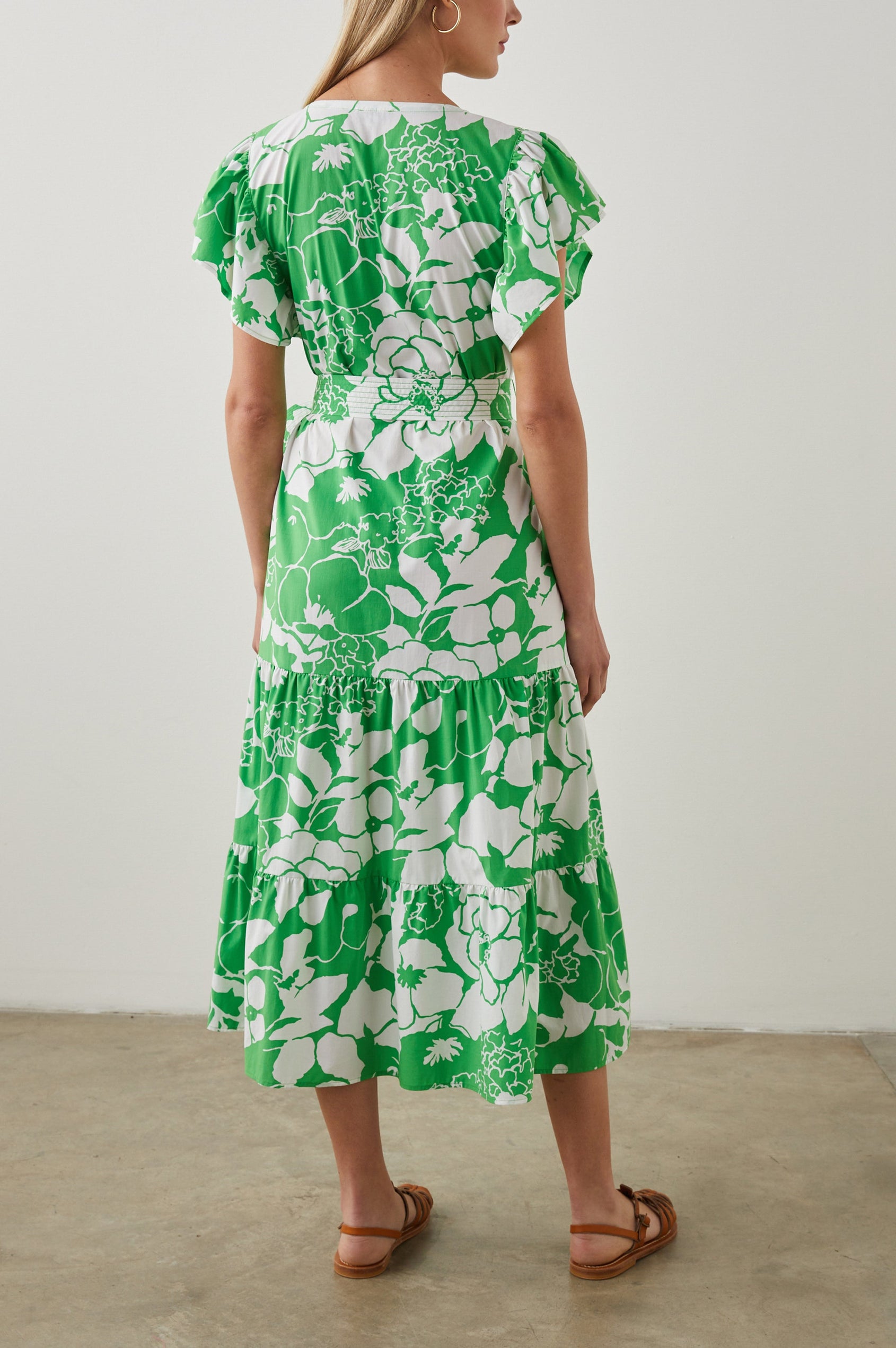 Gia Short-Sleeve Midi Dress with Flutter Sleeves, a V Neck, a Fabric Tie at the Waist, and a Tiered Skirt Green Lotus Colorway, Green and White Flowers - Back Full Body View Featured on Model