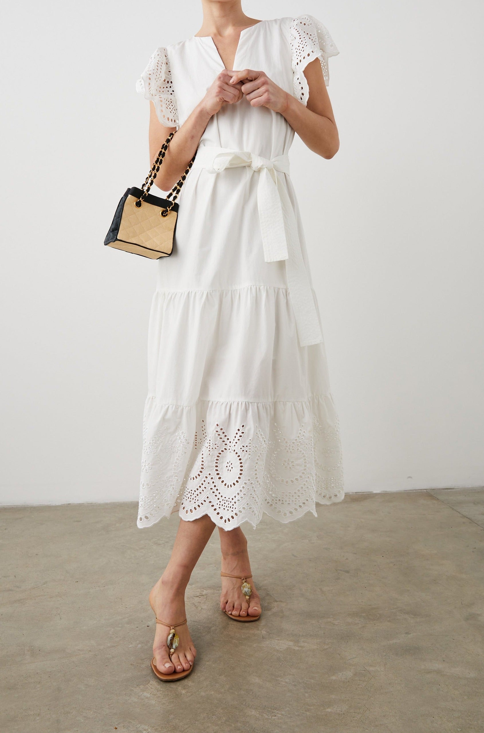 Gia Short-Sleeve Midi Dress with Flutter Sleeves, a V Neck, a Fabric Tie at the Waist, a Tiered Skirt and Eyelet Detail on the Sleeves and Hem in White Colorway - Front Full Body View Featured on Model
