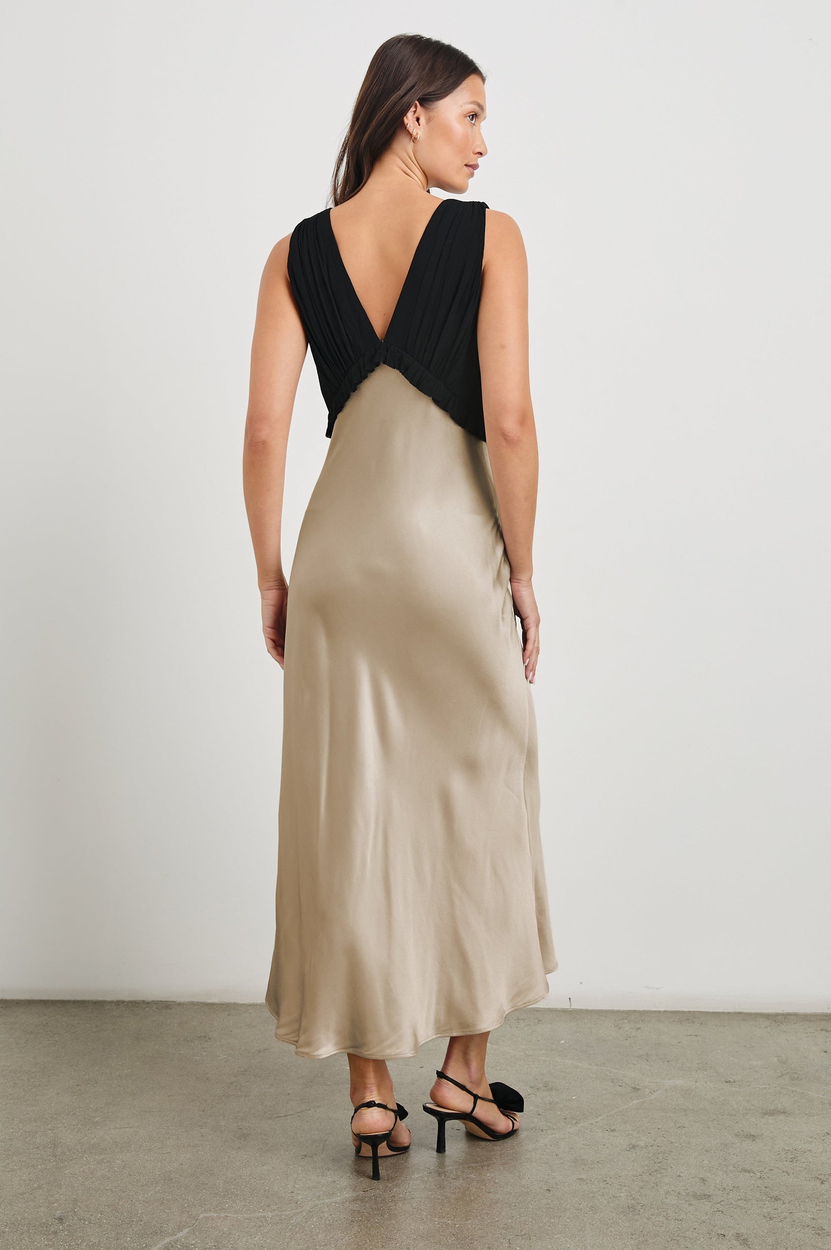 Gilda Sleeveless Midi Dress with Wide Shoulder Straps, a Deep V Neck, and a Bodice with Ruching and Ruffles along the Bottom Edge in Champagne Colorway, with a Black Bodice - Back Full Body View Featured on Model