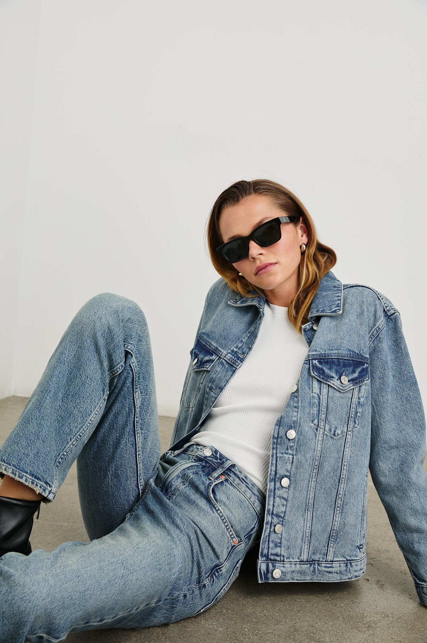 Grove Boyfriend Trucker Denim Jacket with Button Closure, Two Front Pockets, Two Chest Button Flap Pockets, Front Vertical Seams in Embossed Indigo Colorway - Front Full Body View Featured on Seated Model  