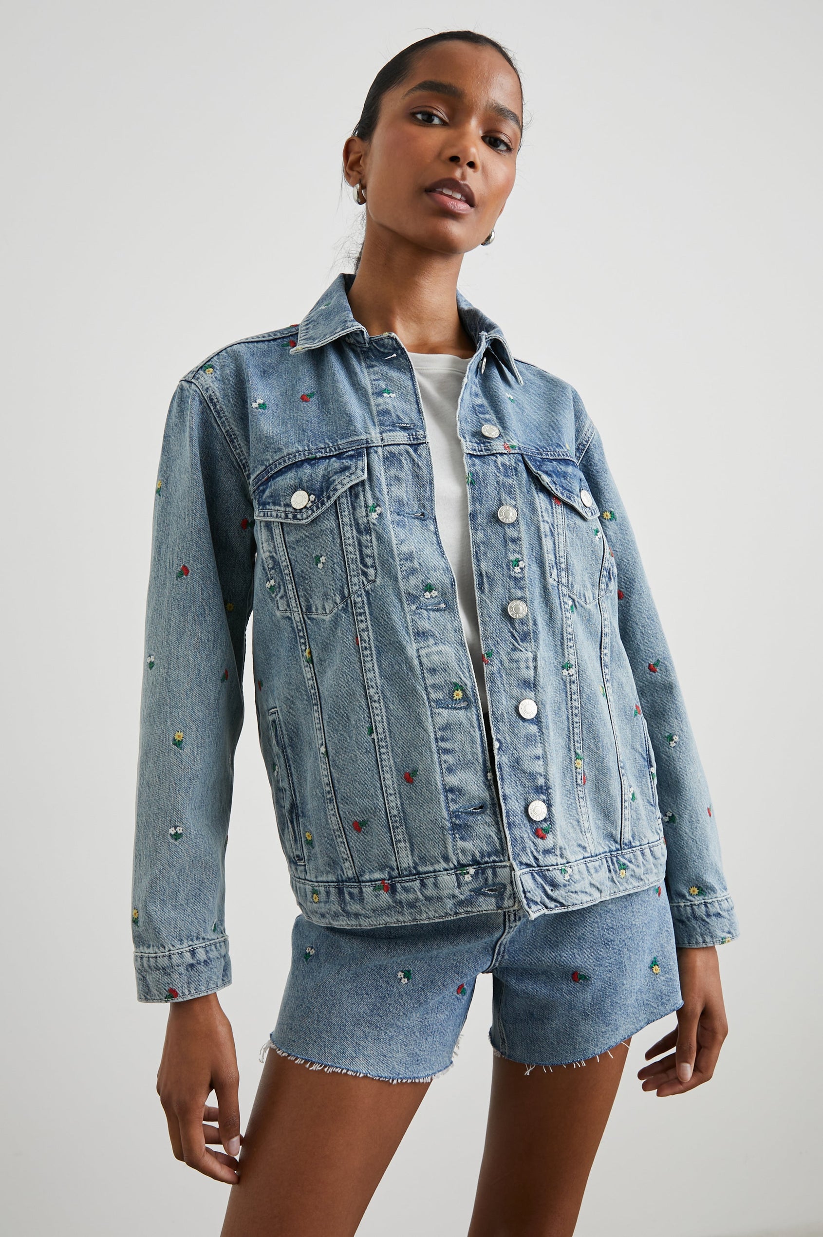 Grove Boyfriend Trucker Denim Jacket with Button Closure, Two Front Pockets, Two Chest Button Flap Pockets, Front Vertical Seams in Flower Field Colorway, with Embroidered Daisies in Yellow, Red and White - Front View Featured on Model  