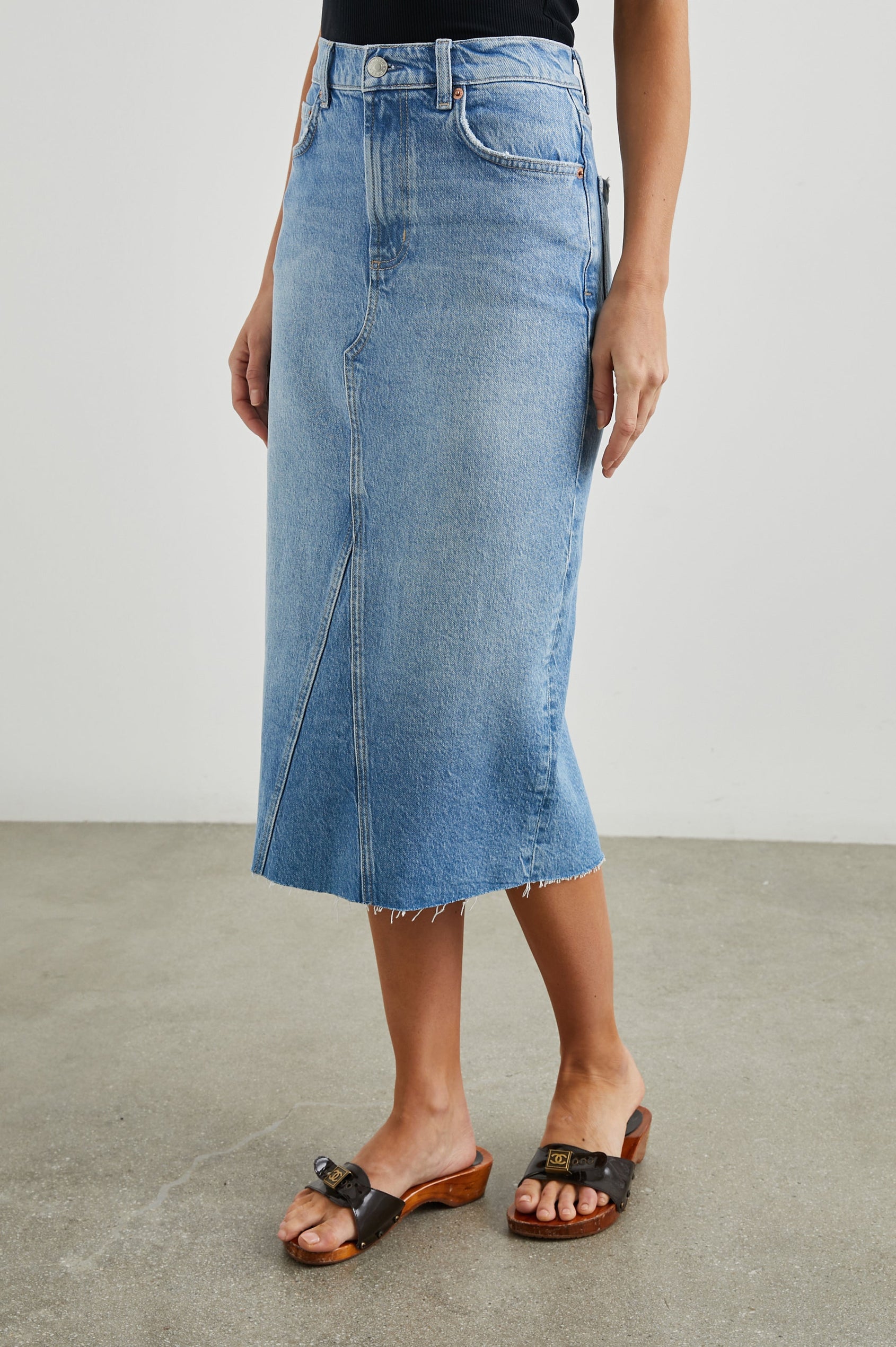Highland Denim Midi Skirt with a Raw Hem, a Back Vent, Additional Front Seams, Belt Loops, Two Front Pockets plus a Coin Pocket and Two Back Patch Pockets in Baja Blue Colorway - Front View Featured on Model 