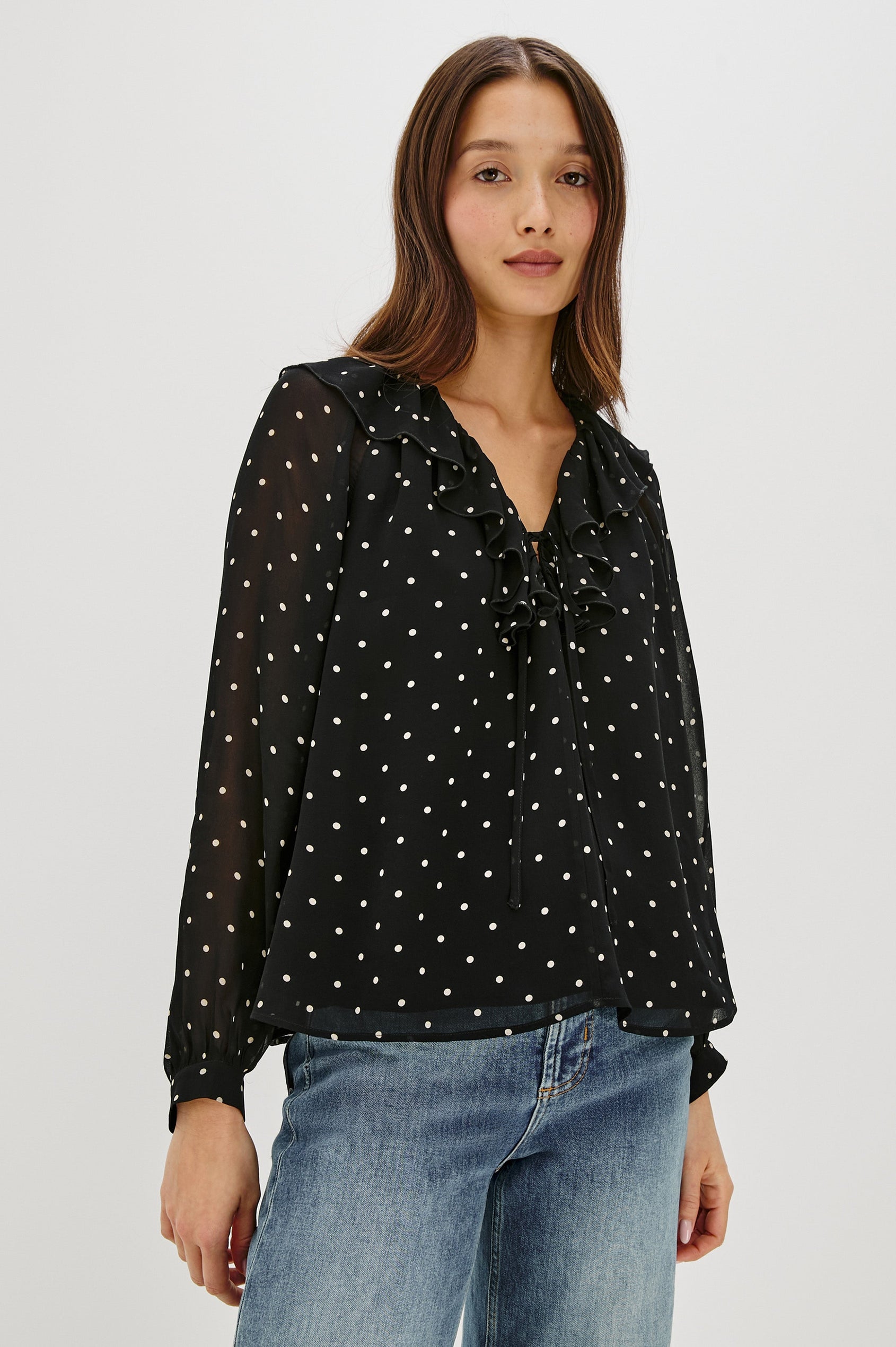 Honora is a lightweight chiffon top with a ruffled neckline and self-tie front closures. The semi-sheer top is partially lined and styled with a soft, feminine silhouette in Polka Dots Colorway - Front View Featured on Model, Untucked
