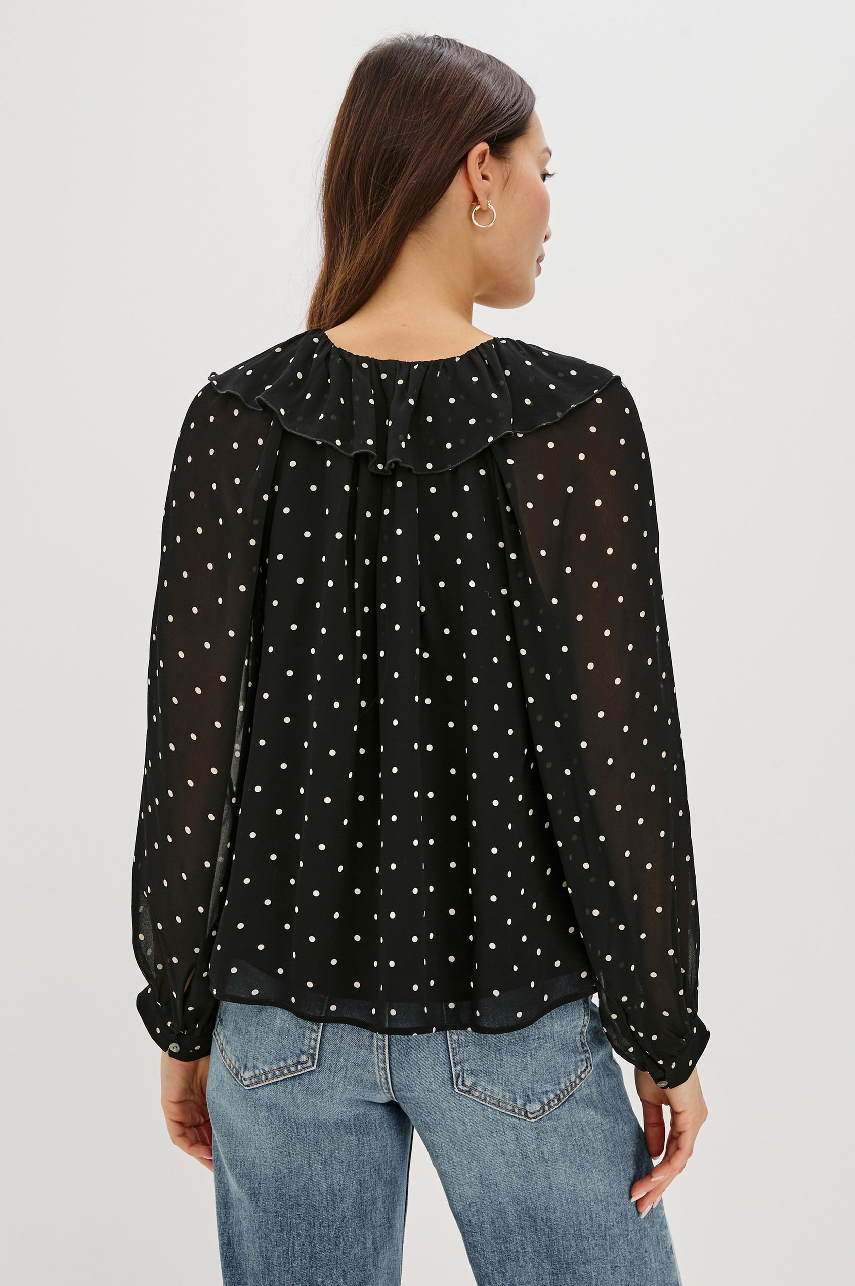 Honora is a lightweight chiffon top with a ruffled neckline and self-tie front closures. The semi-sheer top is partially lined and styled with a soft, feminine silhouette in Polka Dots Colorway - Back View Featured on Model