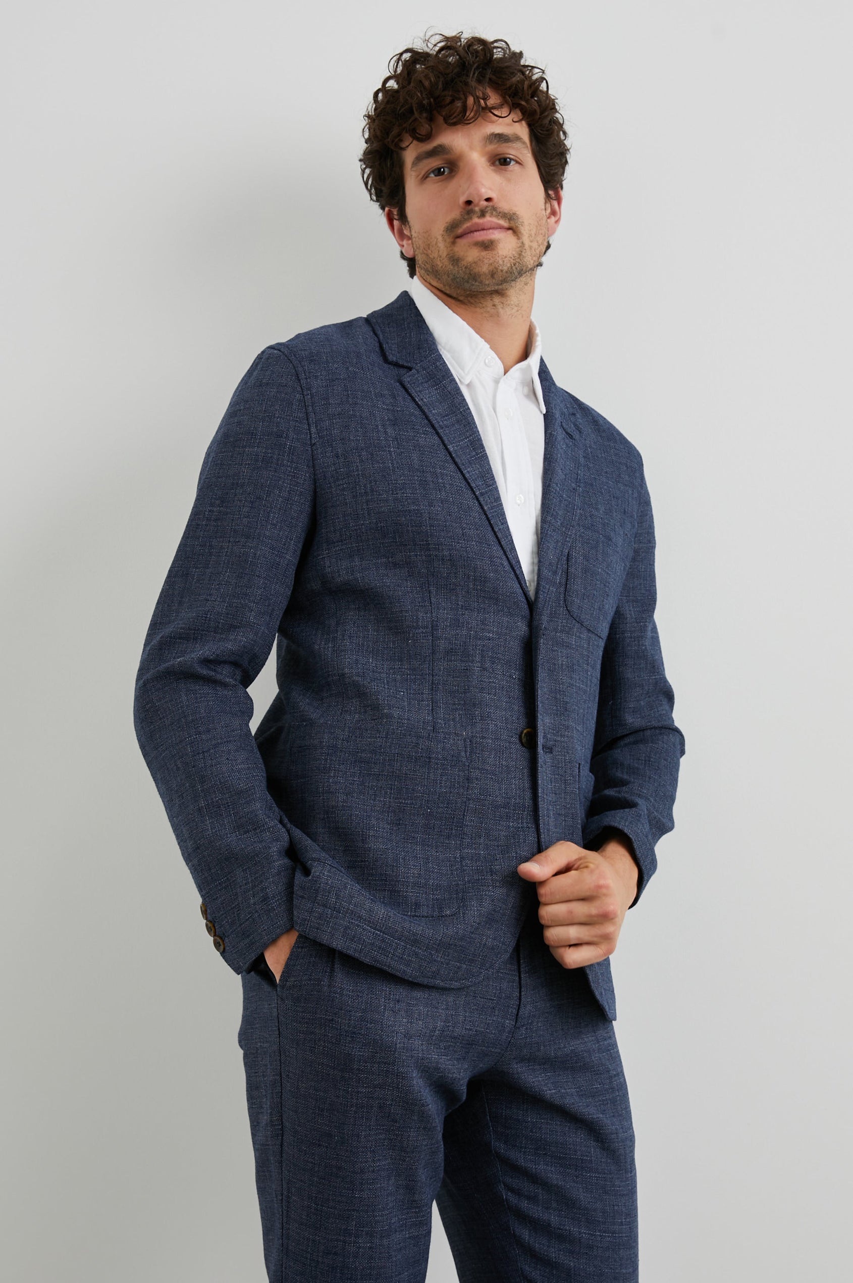 Idris Blazer with Two Button Closure, Two Front Patch Pockets, a Chest Patch Pocket and Three-Button Cuffs in Navy Melange Colorway - Front View Featured on Model