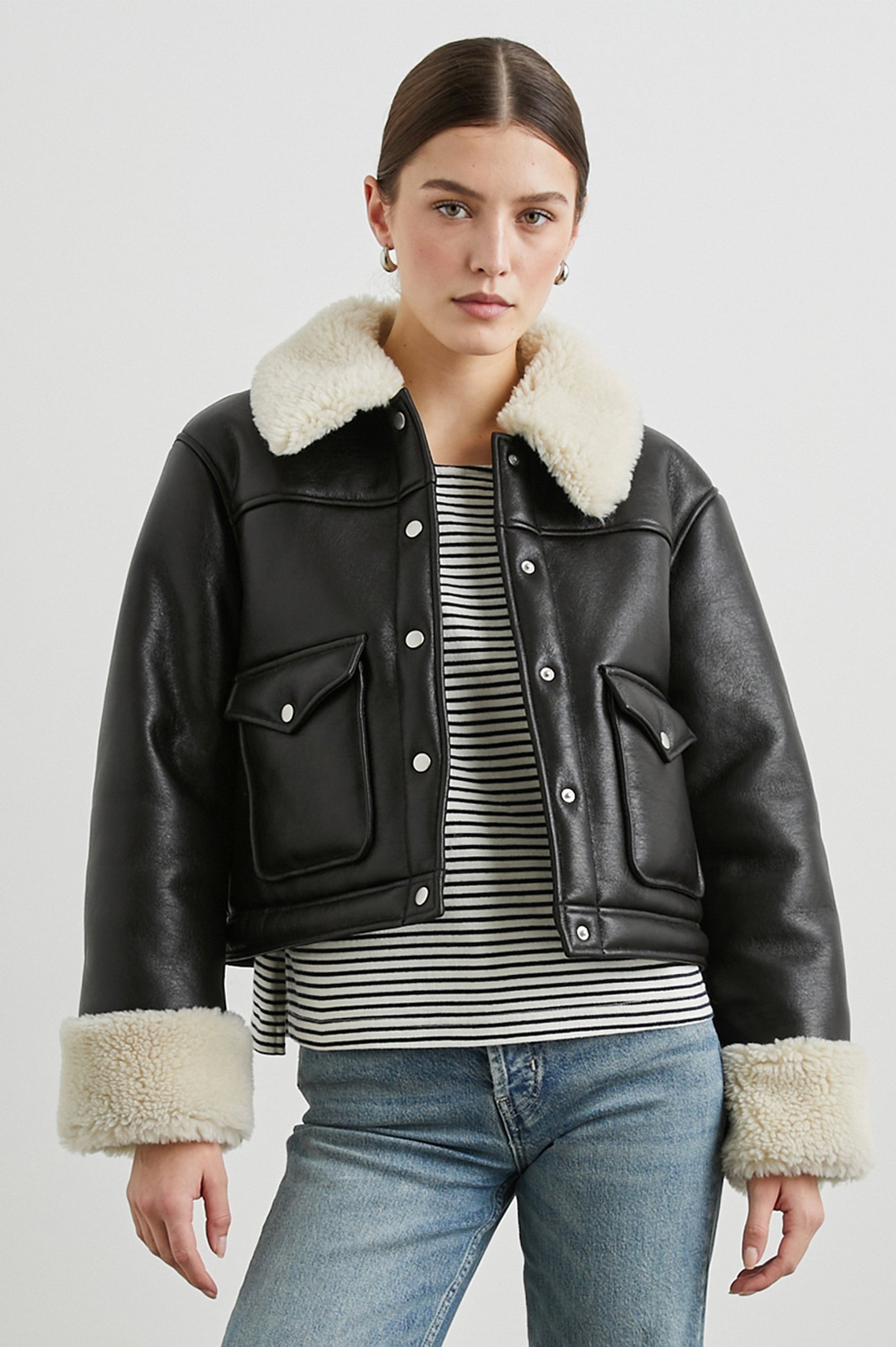 Imani Cropped Faux Leather Jacket with Silver-Toned Snap Closure, Two Front Snap Flap Pockets and Ivory Faux Shearling Lining, Collar and Cuffs in Black Ivory Colorway - Front View Featured on Model  