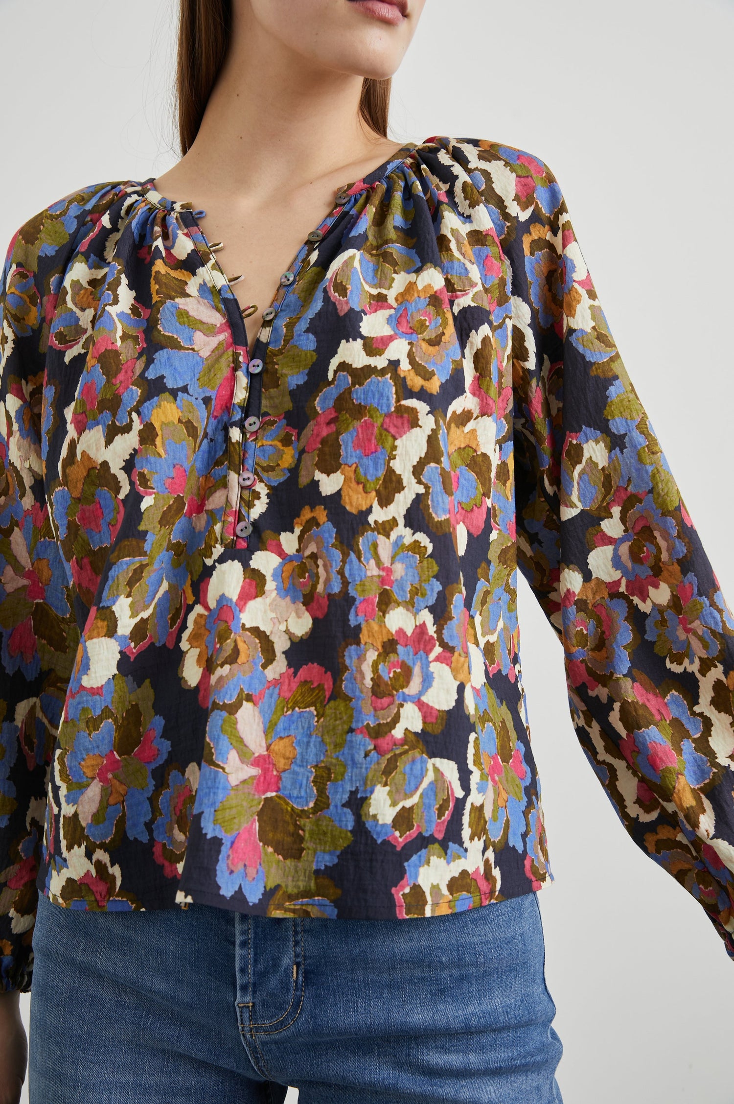 Indi Top with a V Neckline with a Button Placket, Pleating at Back Neckline and Elastic Cuffs in Navy Wildflower Colorway, with blue, gold, green and cream flowers on navy - Front untucked View Featured on Model
