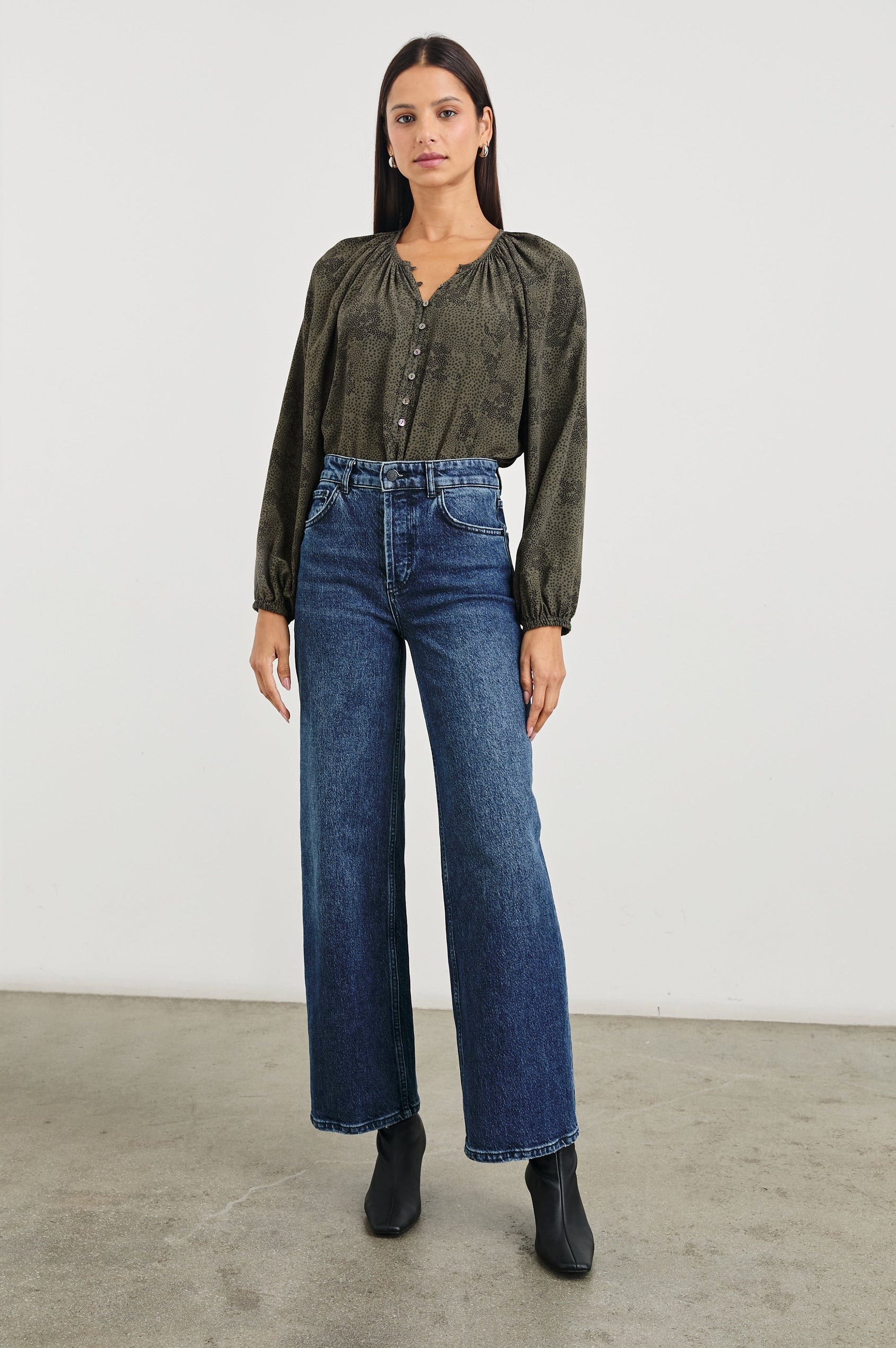 Indi Top with a V Neckline with a Button Placket, Pleating at Back Neckline and Elastic Cuffs in Olive Pebble Colorway, with black pebbles on olive - Front tucked Full Body View Featured on Model