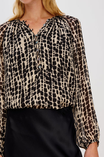 Flowy, 1960s-inspired blouse with a spotted shibori print. The top has sheer, voluminous sleeves with elastic cuffs, natural shell buttons, and a babydoll silhouette. Close Up View on Model.