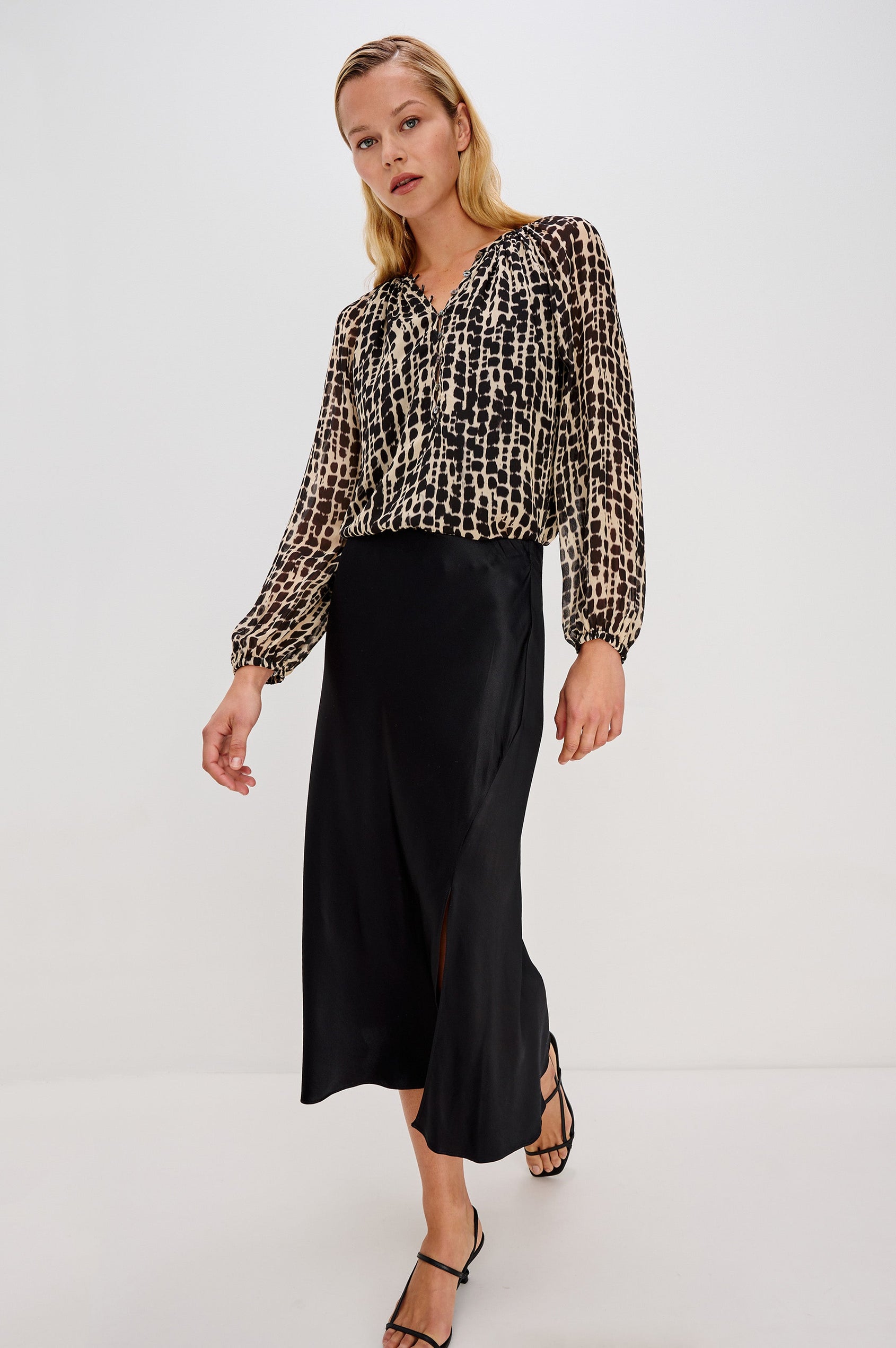 Flowy, 1960s-inspired blouse with a spotted shibori print. The top has sheer, voluminous sleeves with elastic cuffs, natural shell buttons, and a babydoll silhouette. Full Body Front View on Model.