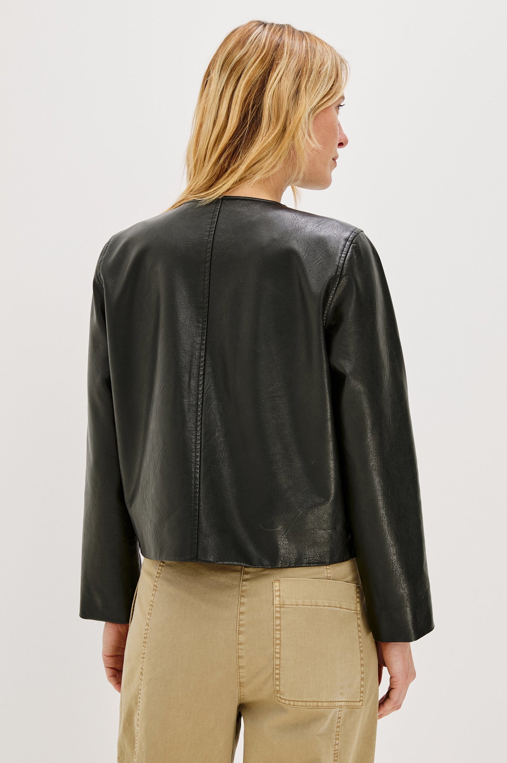 Inka, a cropped, boxy faux leather jacket in a black, slightly distressed finish. The design includes classic chest pockets and a structured silhouette. Back View featured on model