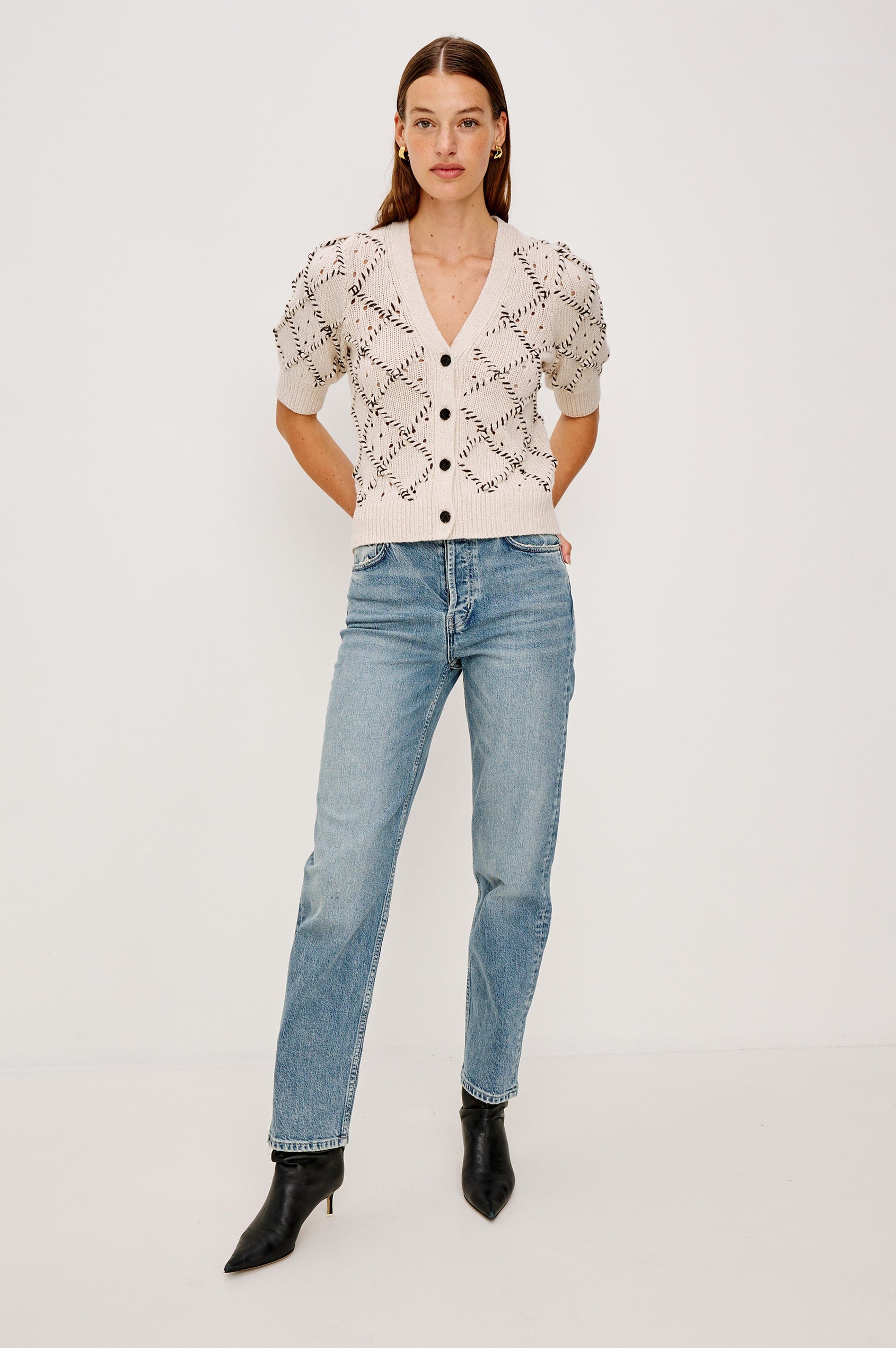 The Isla is a half sleeve cardigan, v-neck and button front with cross hatch rope applique and rib trim in Oat colorway. Front full body view featured on model.