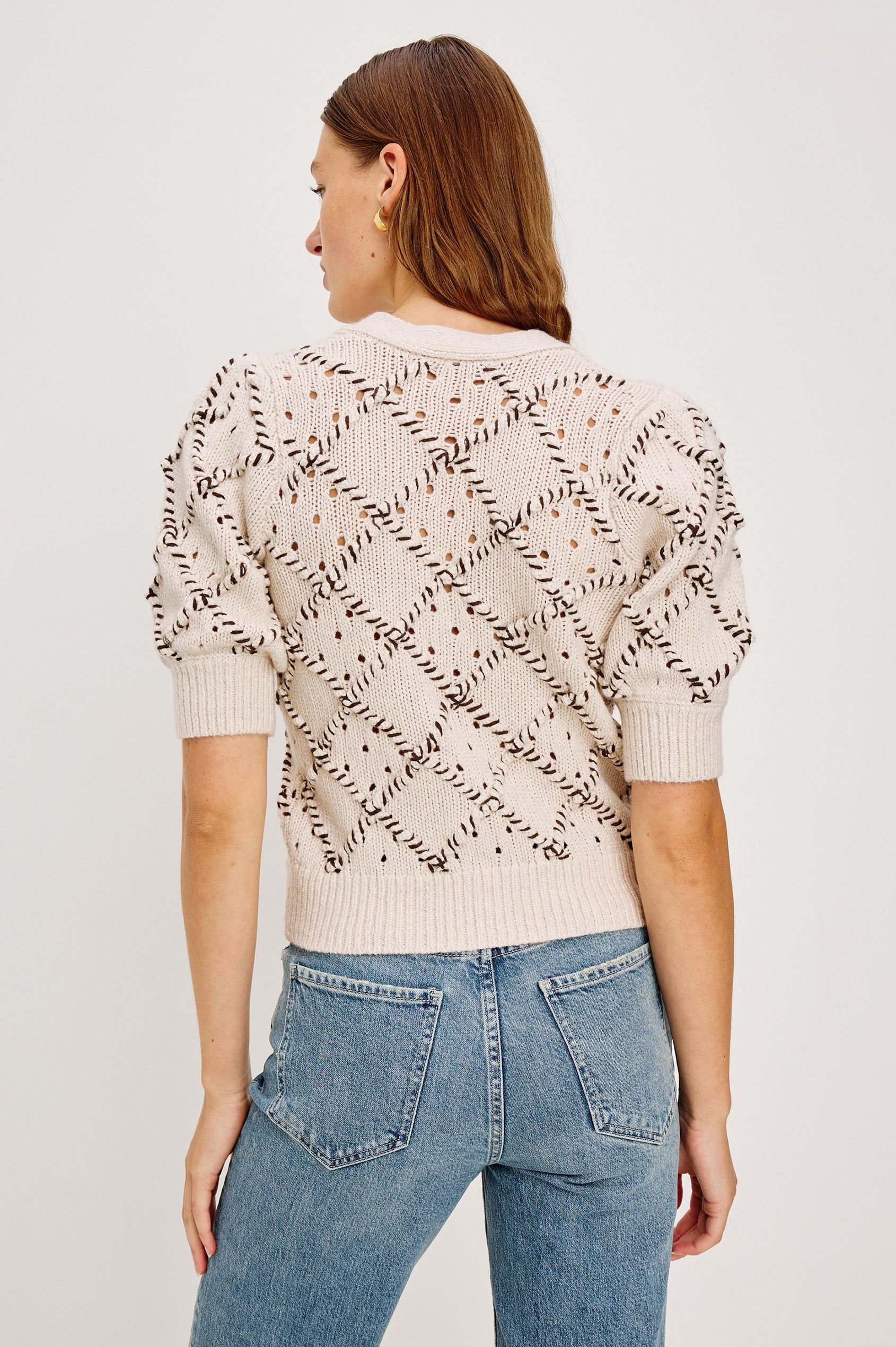 The Isla is a half sleeve cardigan, v-neck and button front with cross hatch rope applique and rib trim in Oat colorway. Back detail view featured on model.