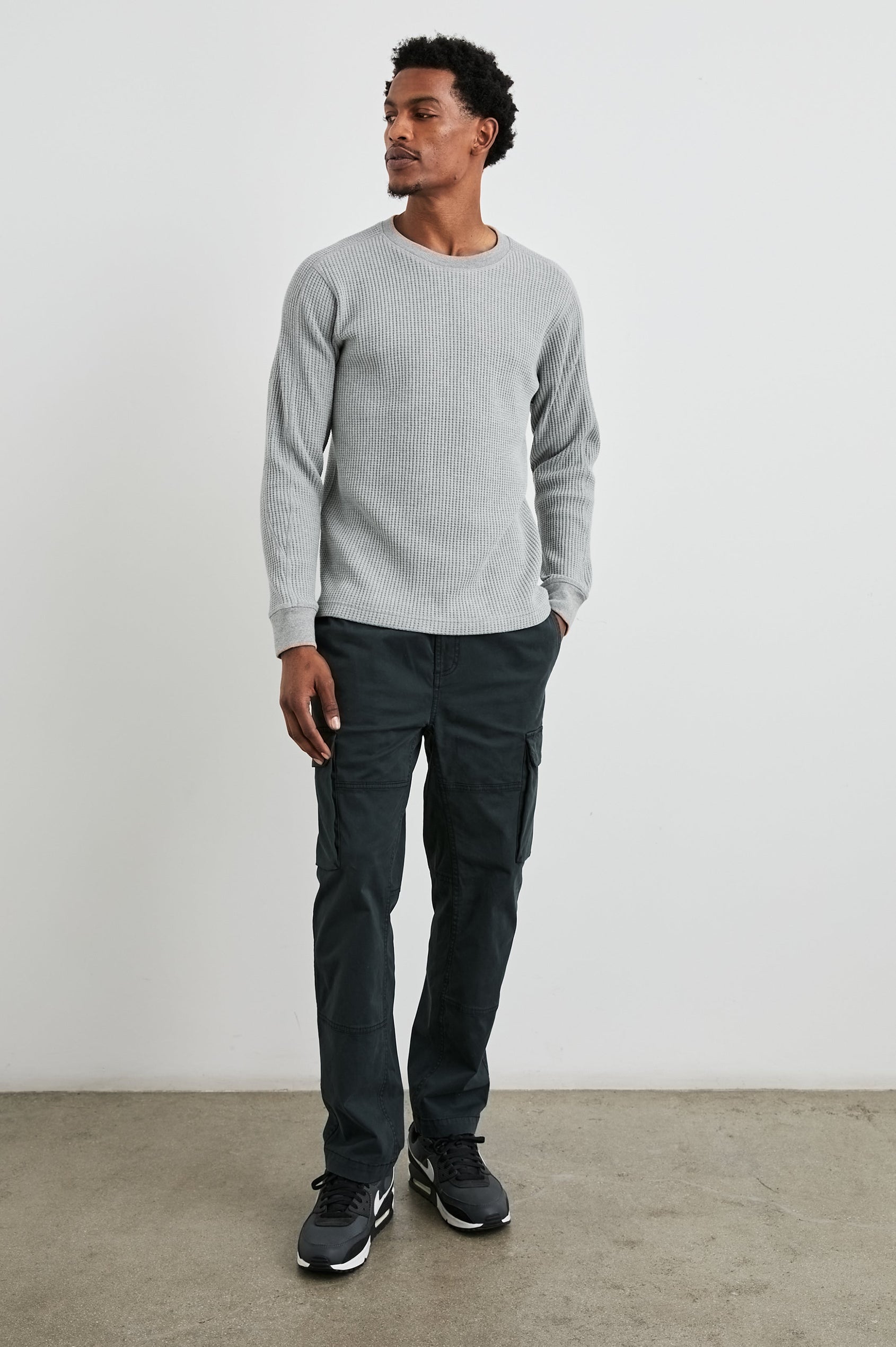 Jaiden Pants with an Elastic, Button Waist with Zip Fly, Two Front Pockets, Two Side Flap Pockets, and Two Back Flap Pockets in Black Colorway - Front Full Body View Featured on Model