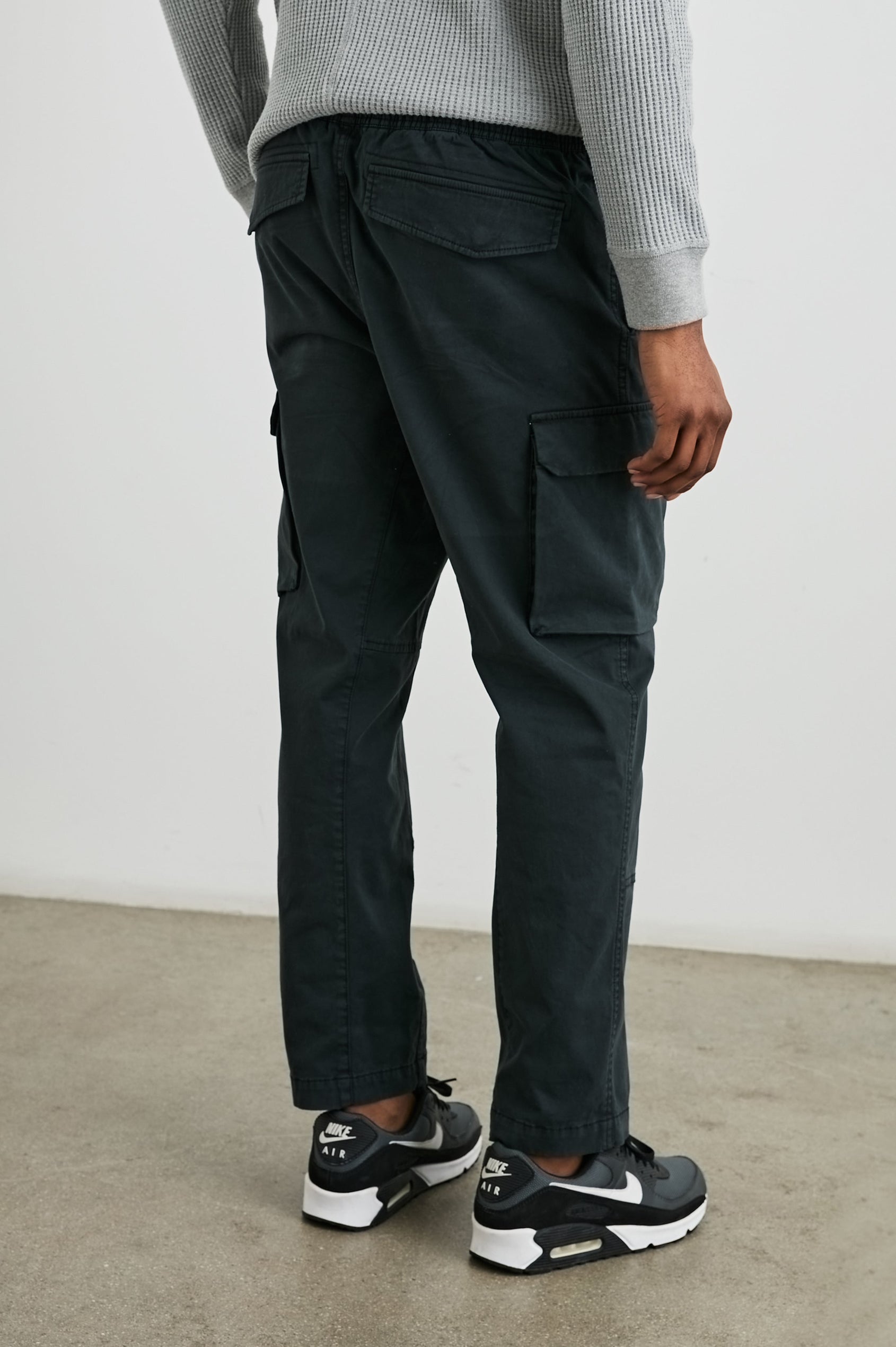 Jaiden Pants with an Elastic, Button Waist with Zip Fly, Two Front Pockets, Two Side Flap Pockets, and Two Back Flap Pockets in Black Colorway - Back View Featured on Model