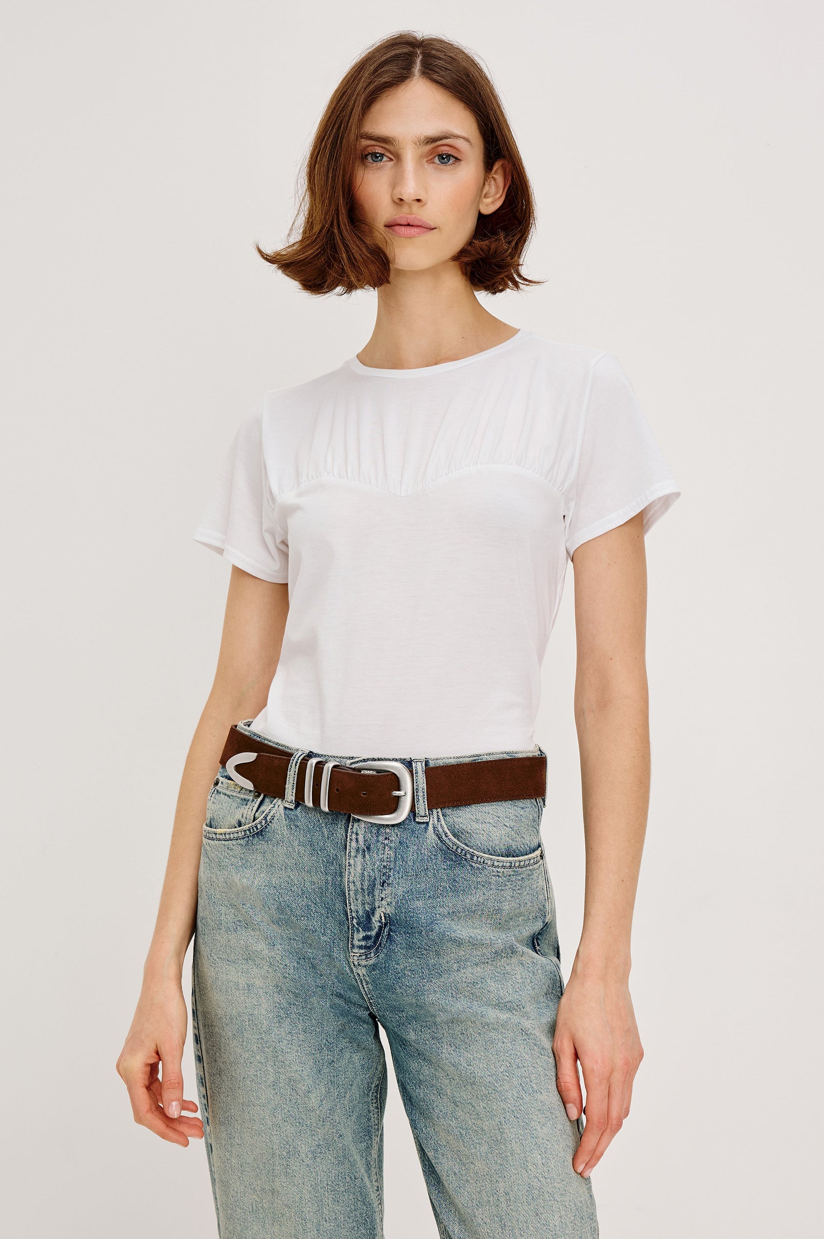 Janis short-sleeve cotton t-shirt with a sweetheart neckline and gathered, shirred detailing at the chest in White Colorway - front view featured on model with shirt tucked in and styled with a western belt.
