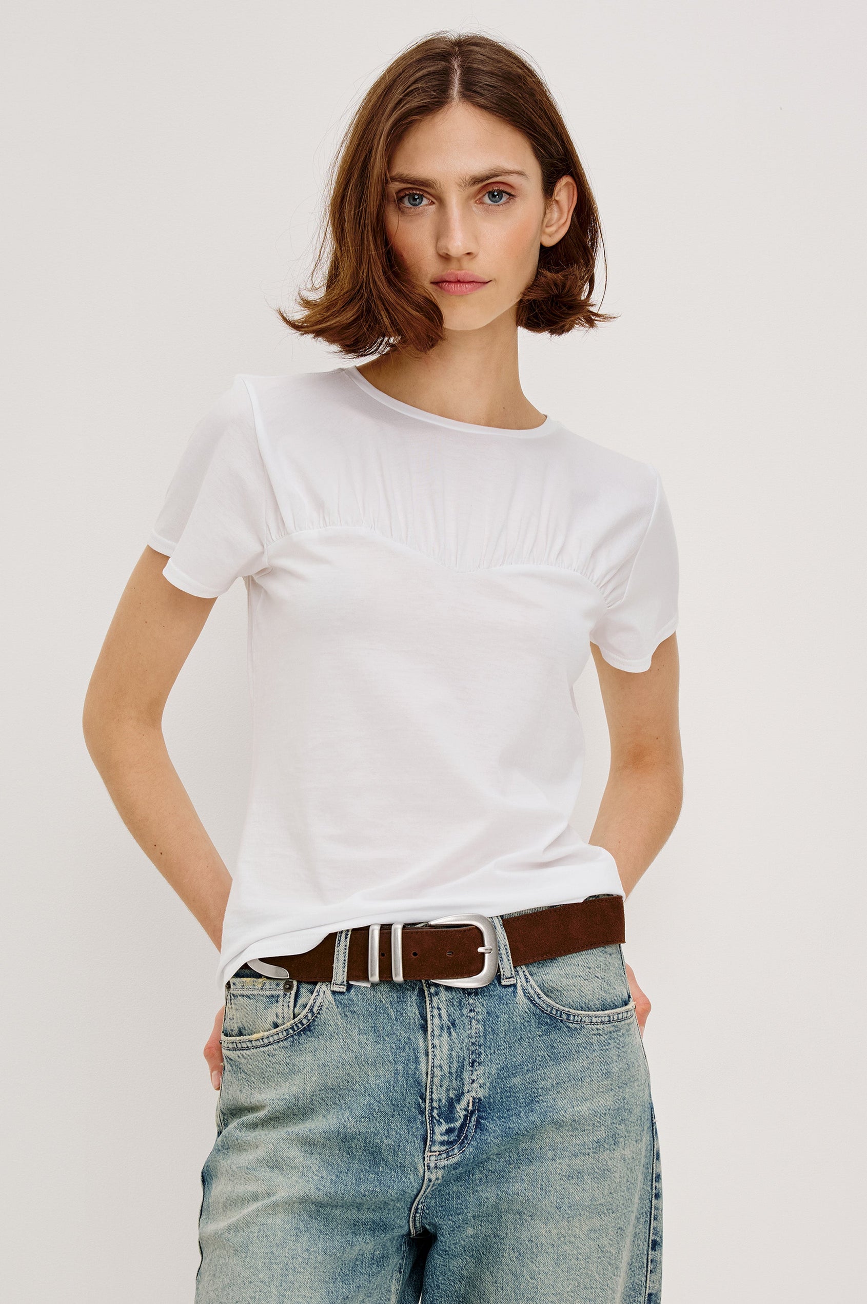Janis short-sleeve cotton t-shirt with a sweetheart neckline and gathered, shirred detailing at the chest in White Colorway - front view featured on model with shirt partially tucked in and styled with a western belt.