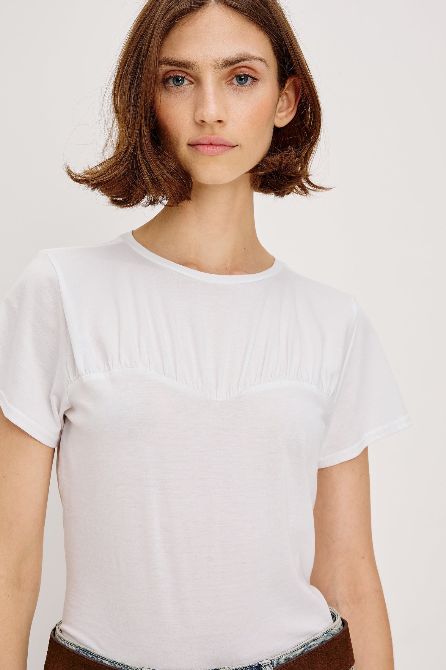 Janis short-sleeve cotton t-shirt with a sweetheart neckline and gathered, shirred detailing at the chest in White Colorway - front detailed view featured on model with shirt tucked in and styled with a western belt.