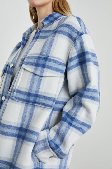 Jaro Mid-Thigh Length Coat with Snap Closure, Snap Cuffs, Two Chest Flap Pockets, Two Front Pockets and Side Hem Slits in Ivory Bay Colorway, an Ivory and Blue Plaid - Side View Featured on Model 
