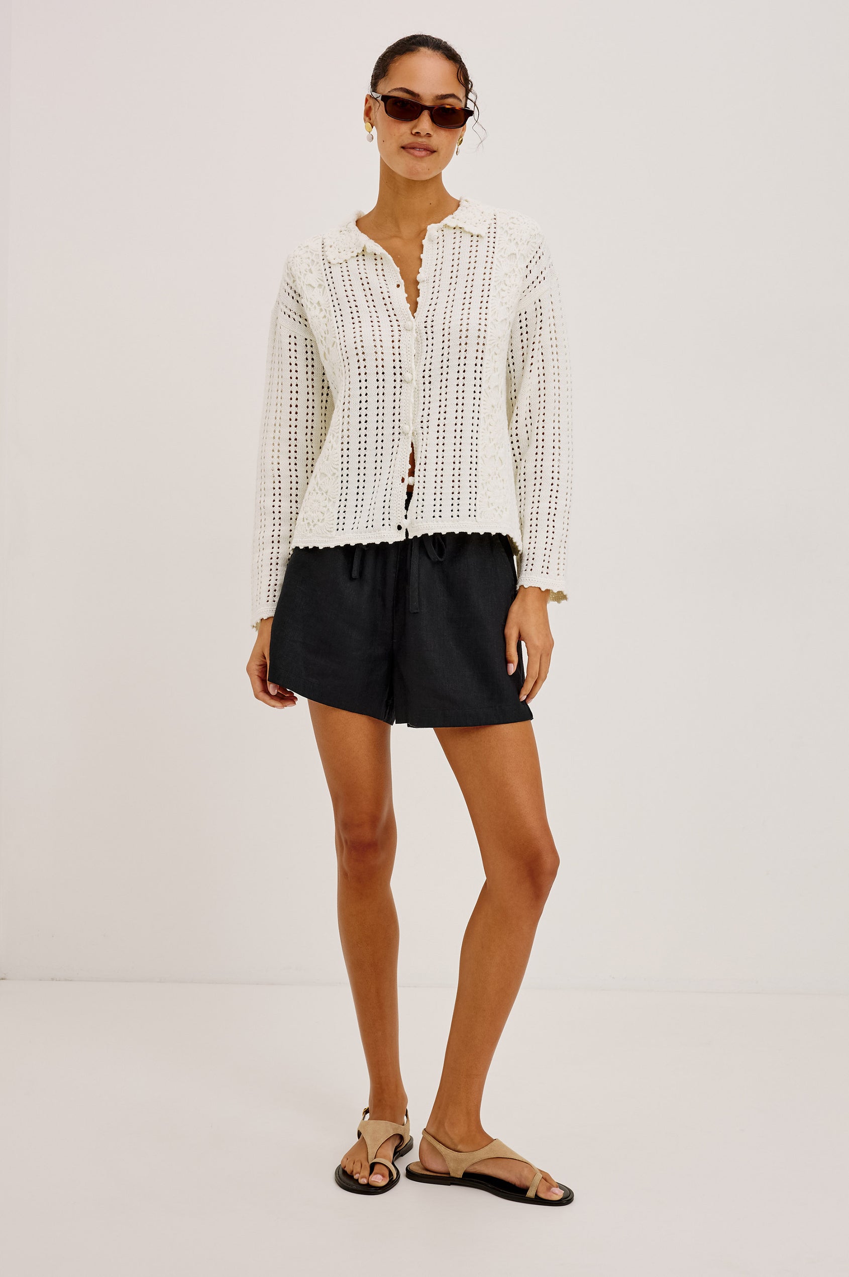 Jenni Cardigan Sweater in Open Weave Cotton Blend Pointelle Knit With Long Sleeves, Crochet Button-Loop Closures, Floral Detailing, and Scalloped Trim in Ivory Colorway - Full Body Front View Featured on Model
