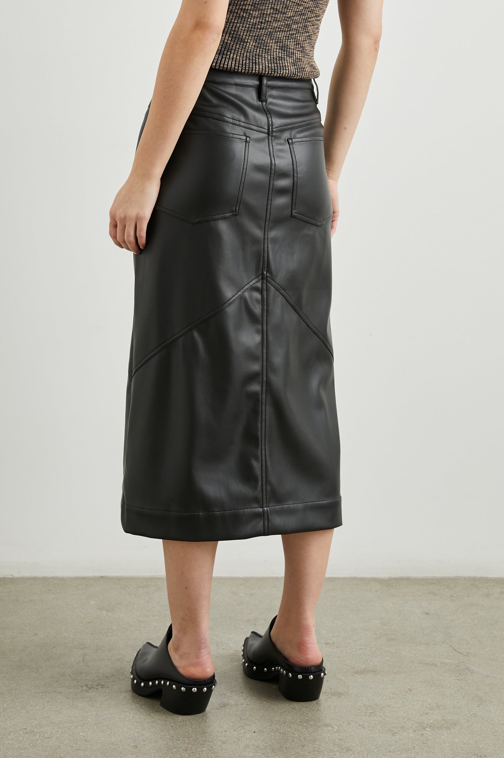 Jennifer Faux Leather Midi Skirt with a Center Slit, Belt Loops and Two Back Patch Pockets in Black Colorway - Back View Featured on Model 