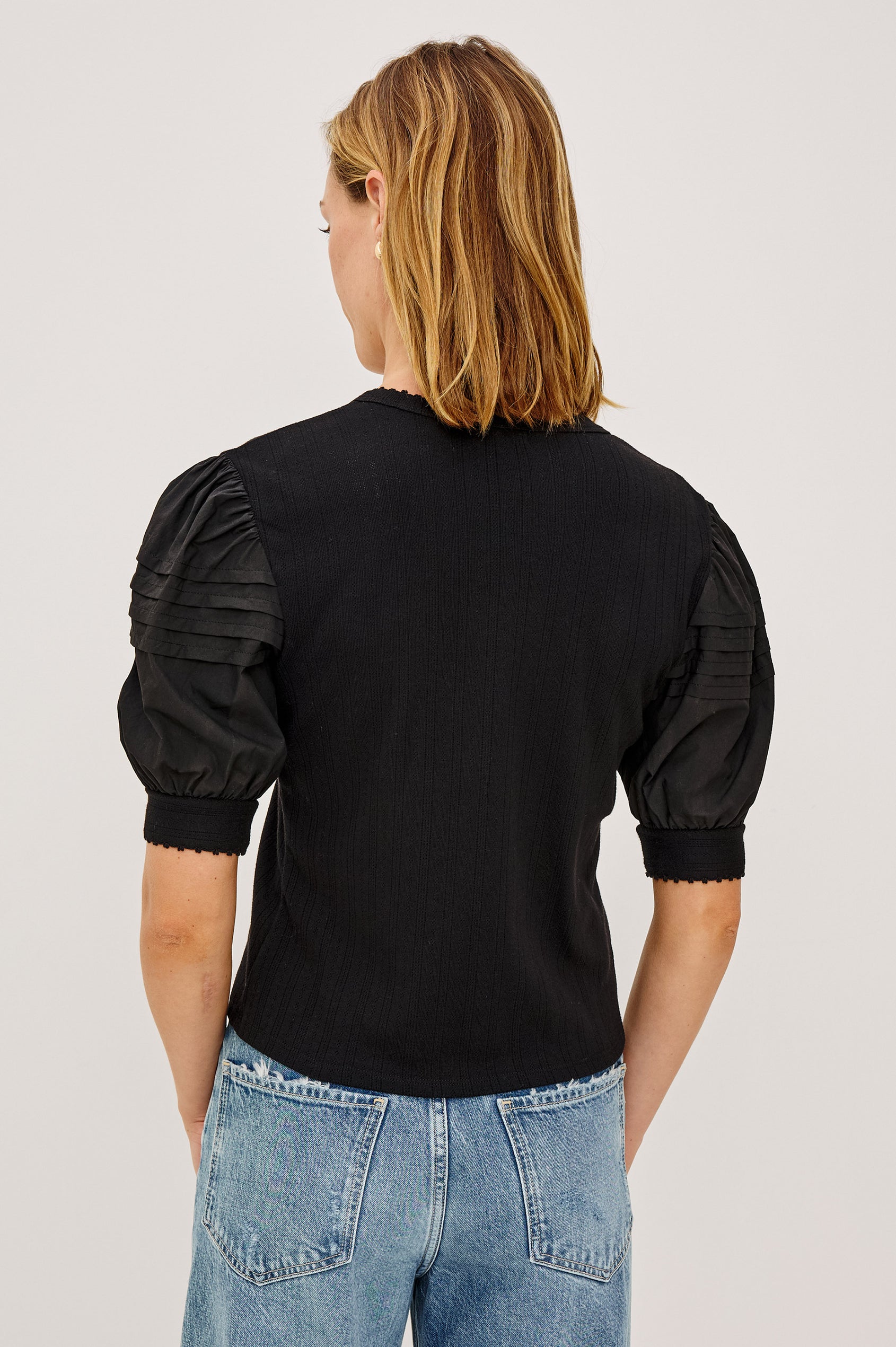 Jessie Top in Pointelle With V-Neckline, Front Buttons, Short Cuffed Puff Sleeves, and Relaxed Fit in Black Colorway - Upper Body Back View Featured on Model