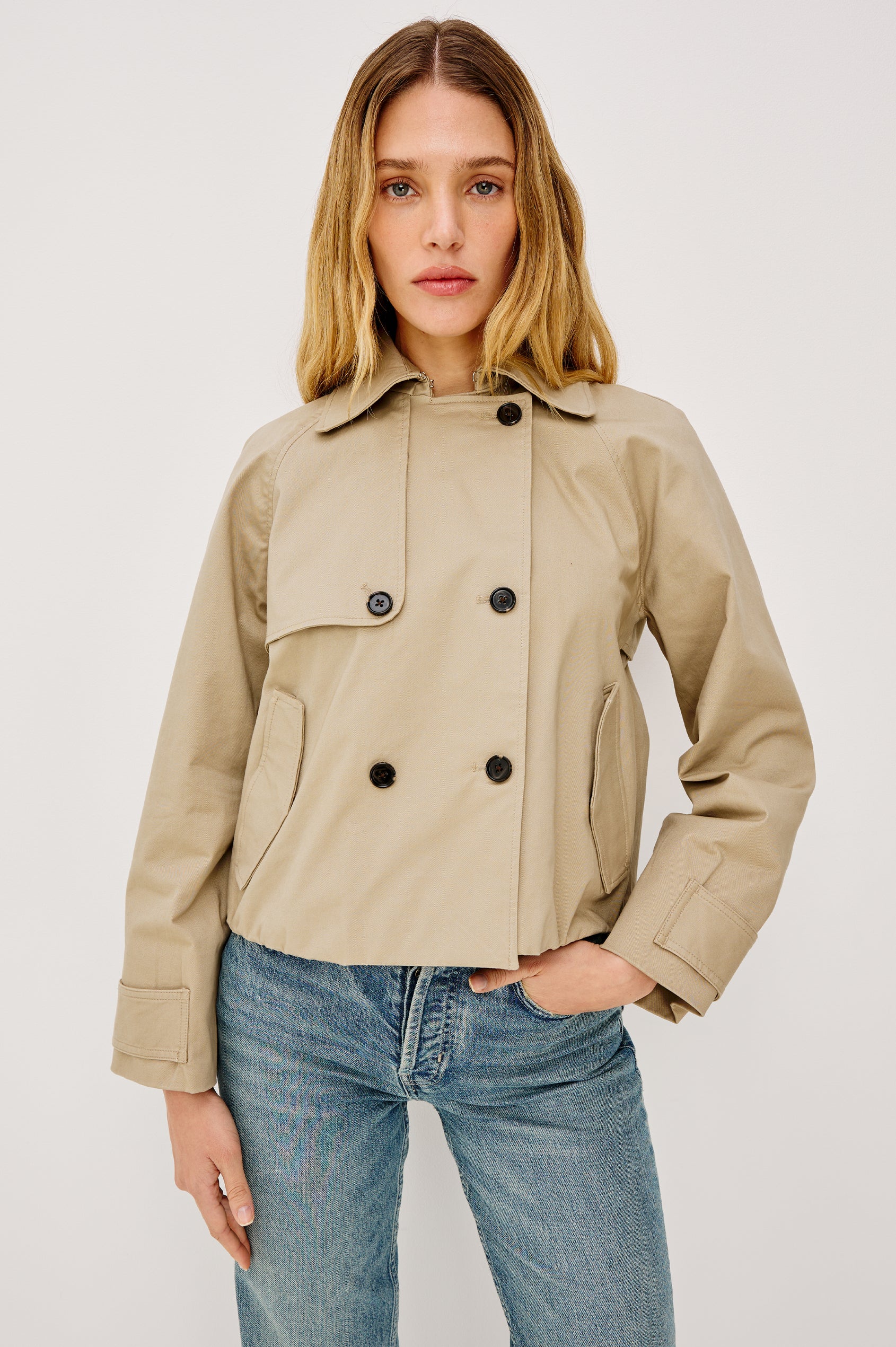 Jett Double Breasted, Cropped Trench Jacket, Lapel, Adjustable Cuff Belt, Side Pockets and Elasticated Hem in Taupe Colorway. Front Full Body View Featured on Model.